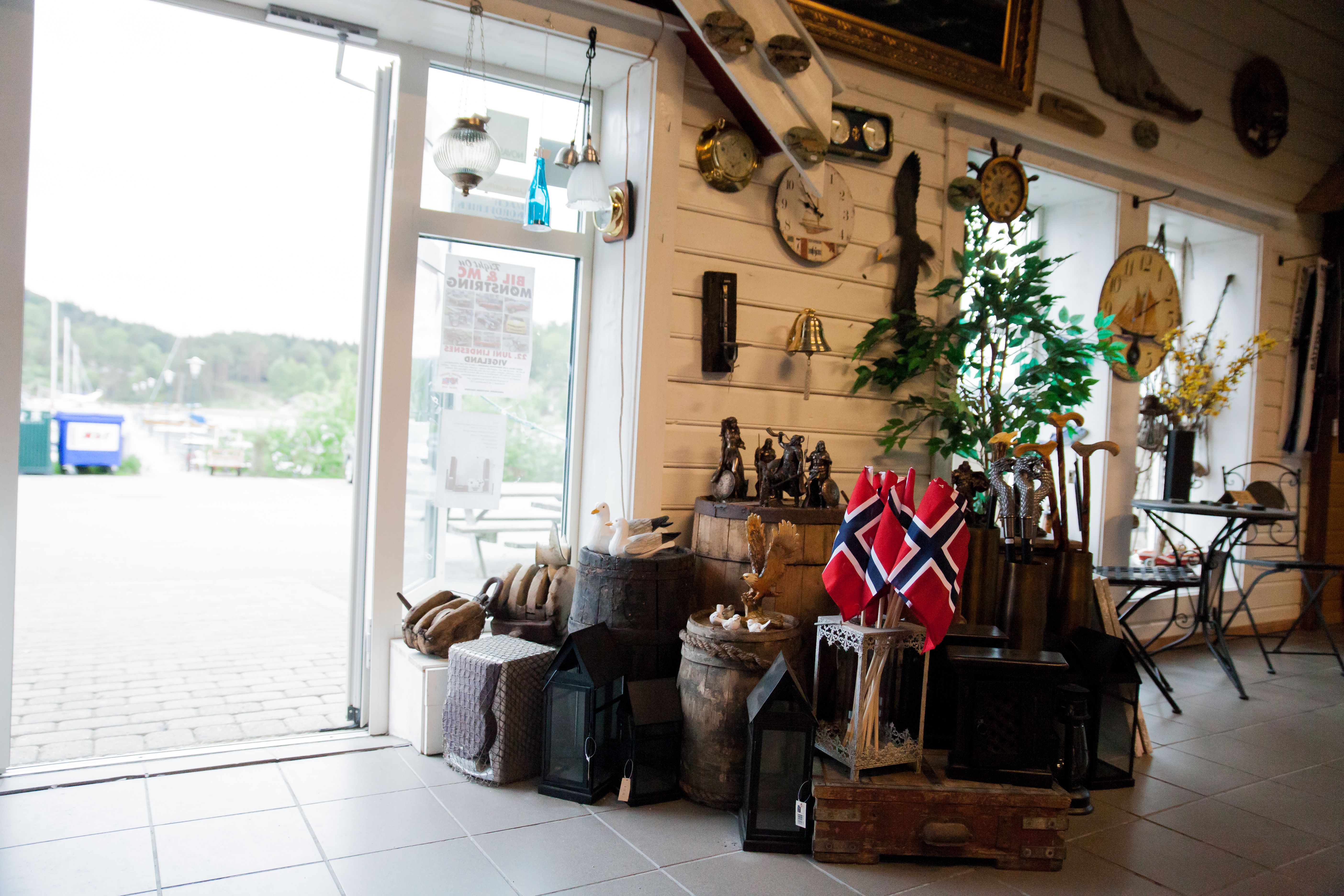 The entrance area is decorated with many old barrels, suitcases, and crates. Small Norwegian flags and wooden walking sticks available for purchase.
