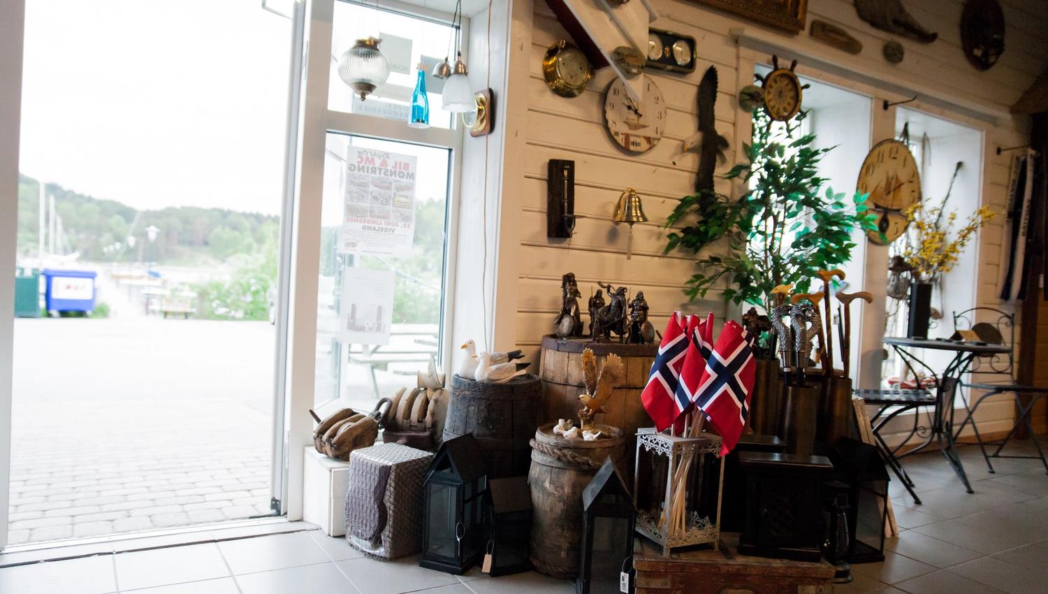 The entrance area is decorated with many old barrels, suitcases, and crates. Small Norwegian flags and wooden walking sticks available for purchase.