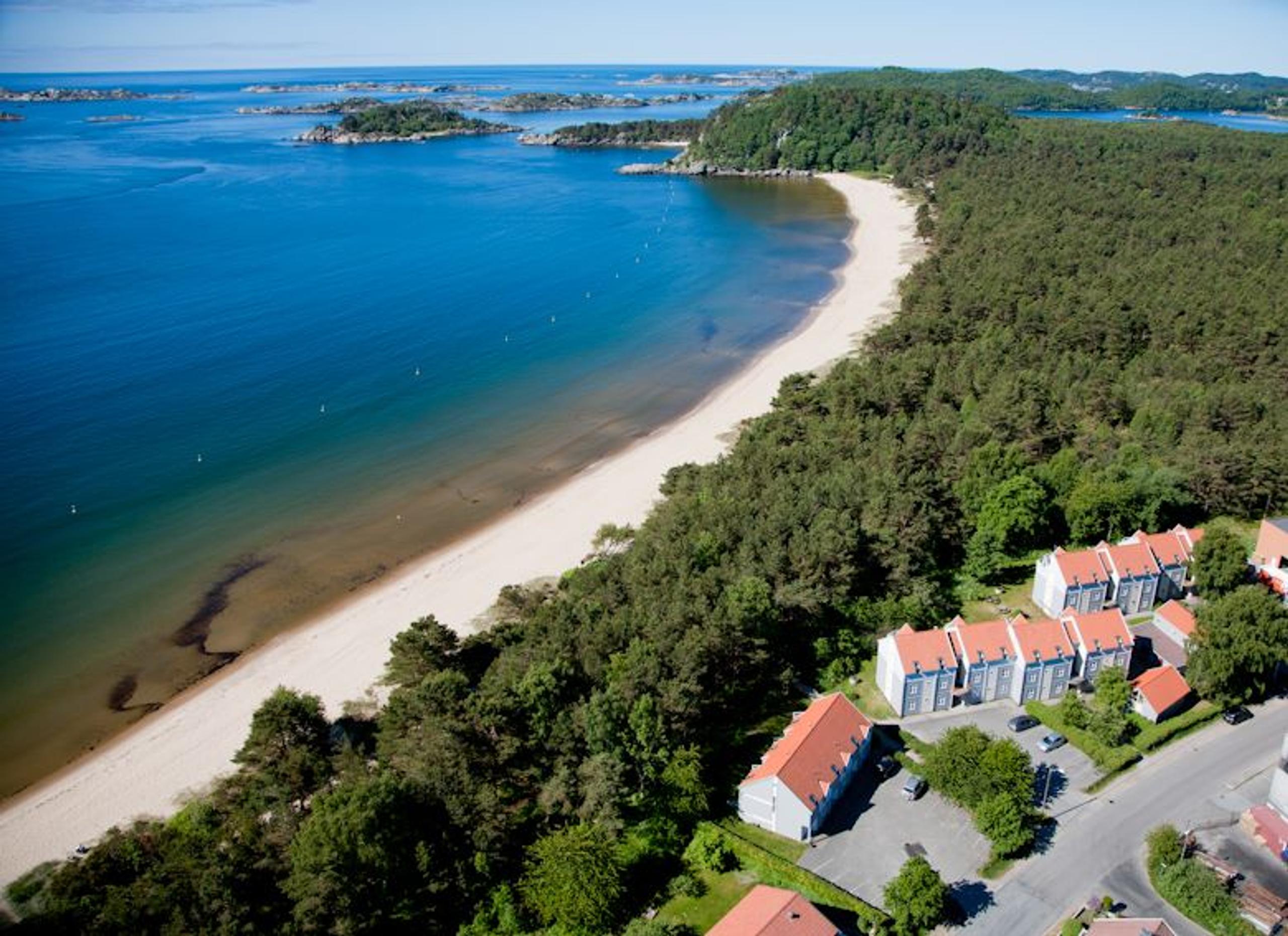 
Holiday resort with a view, beach along the water, and forest lining the shore