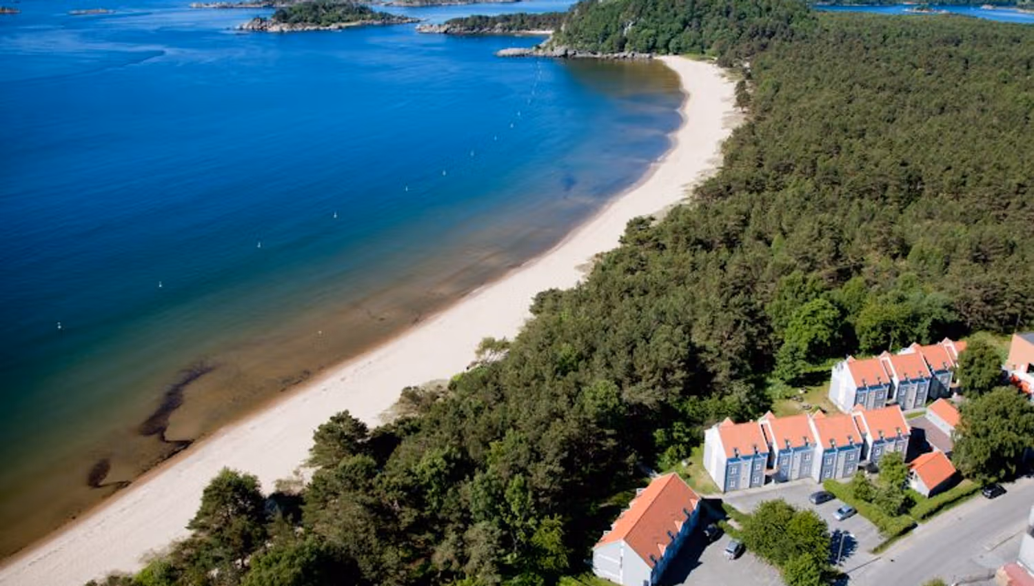 Holiday resort with a view, beach along the water, and forest lining the shore