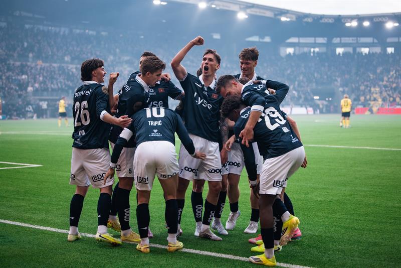 Ten Viking players celebrate a goal in front of a packed crowd
