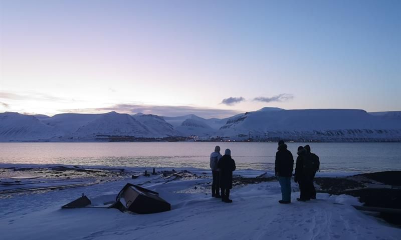 Five people looking towards Longyearbyen and the beautiful light over the city.