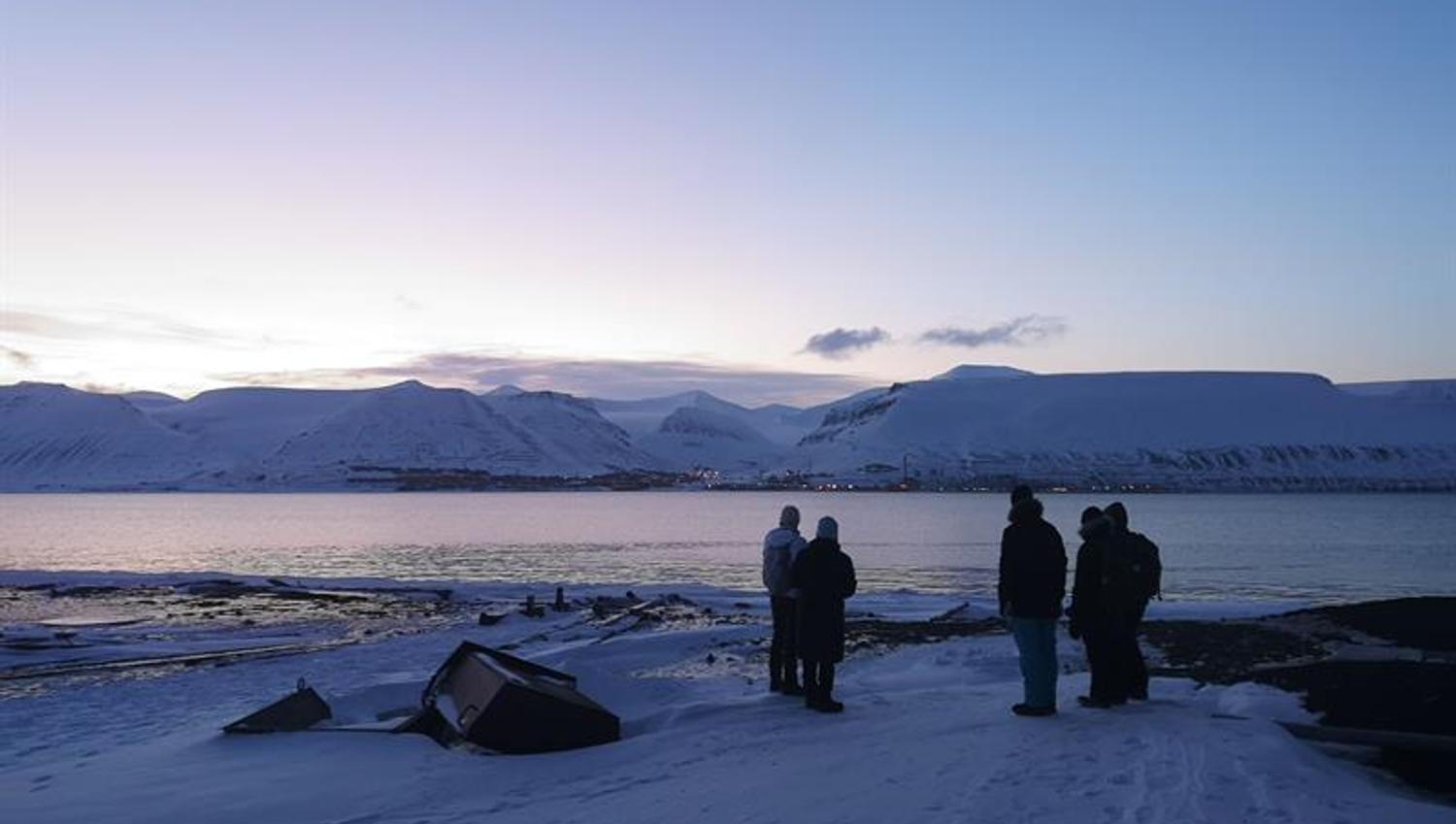 Five people looking towards Longyearbyen and the beautiful light over the city.