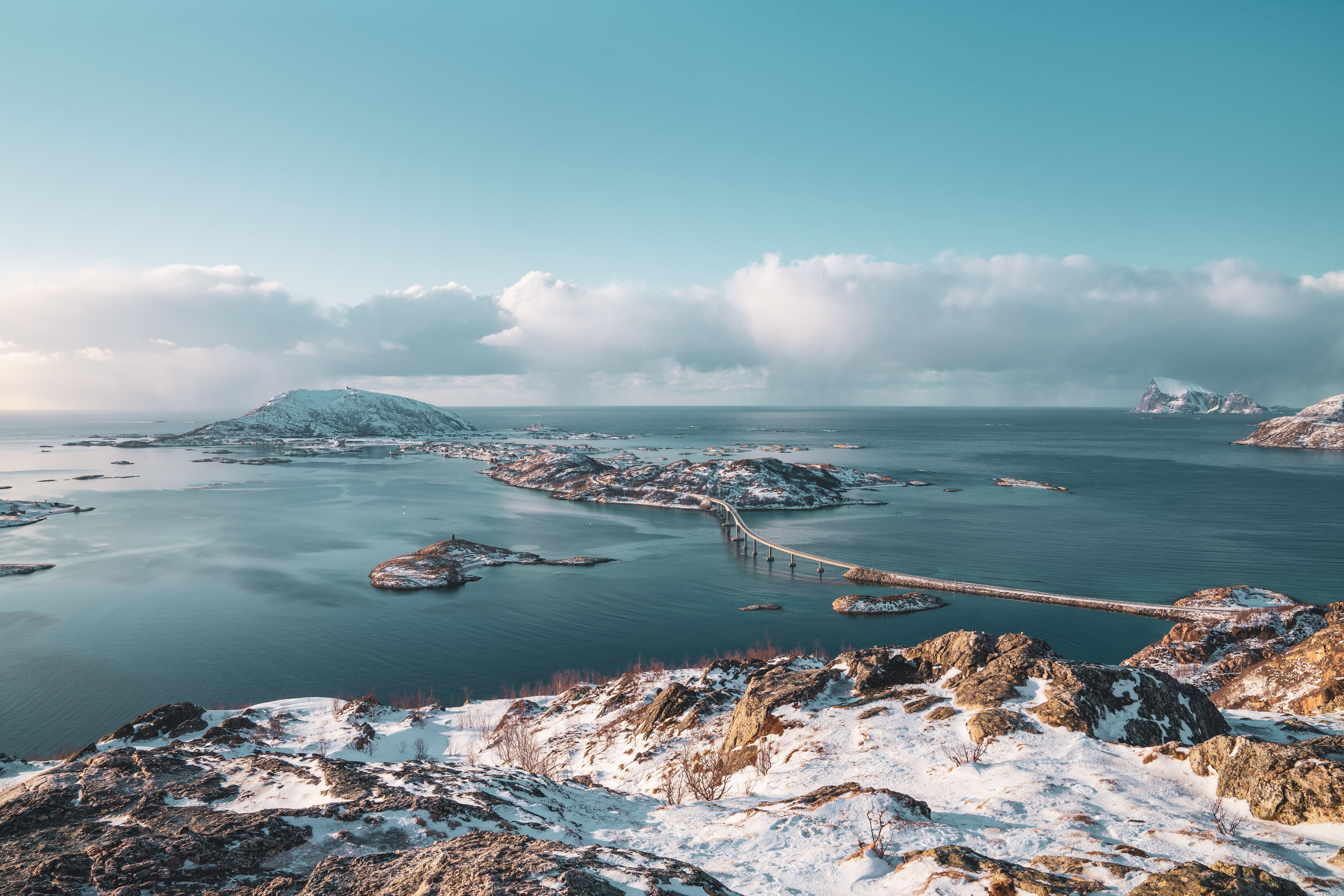 Snowy coastal landscape with bridges between islands and a clear sky in the background