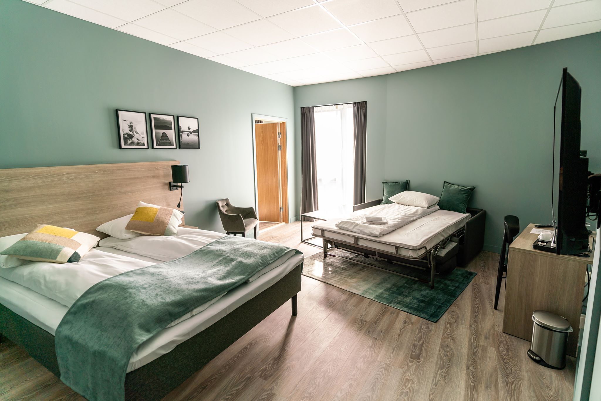 Spacious hotel room with a double bed, single bed, and modern decor.