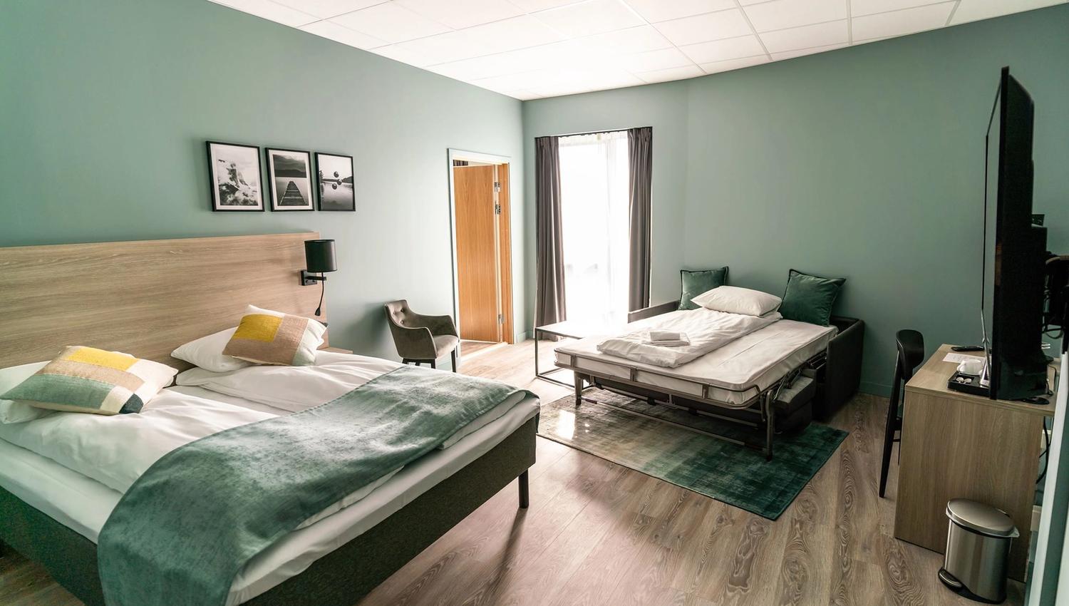 Spacious hotel room with a double bed, single bed, and modern decor.