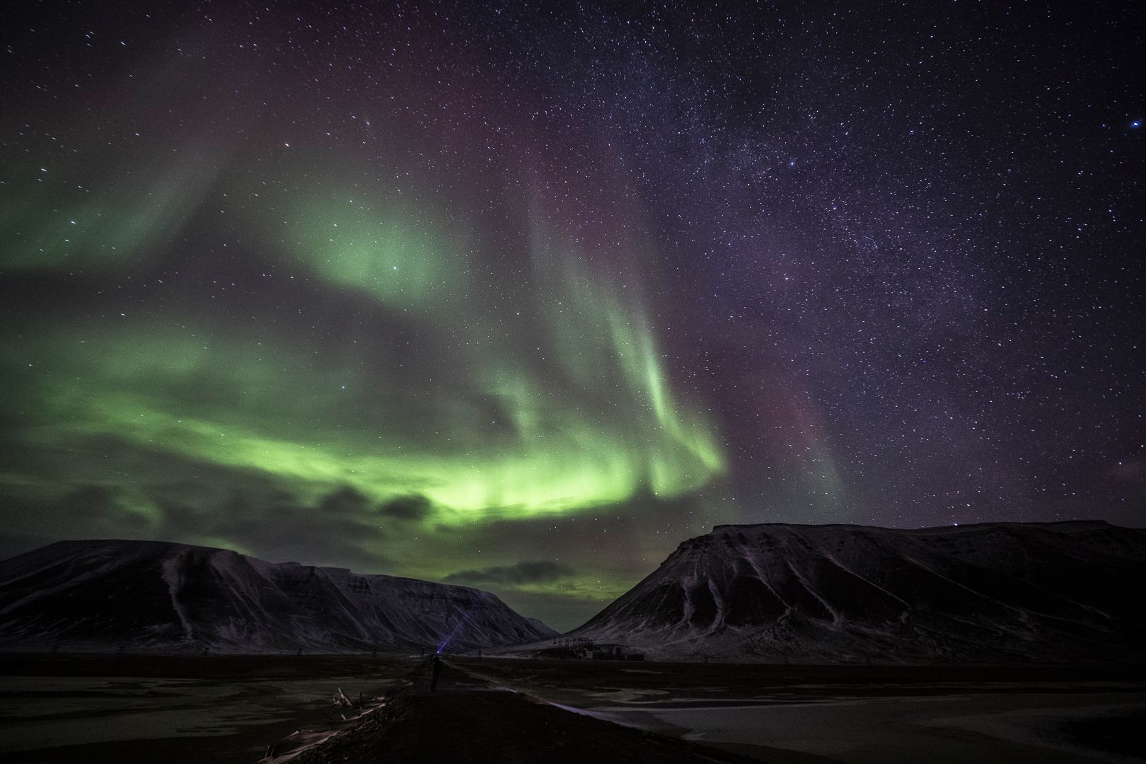 Green northern lights above the mountains