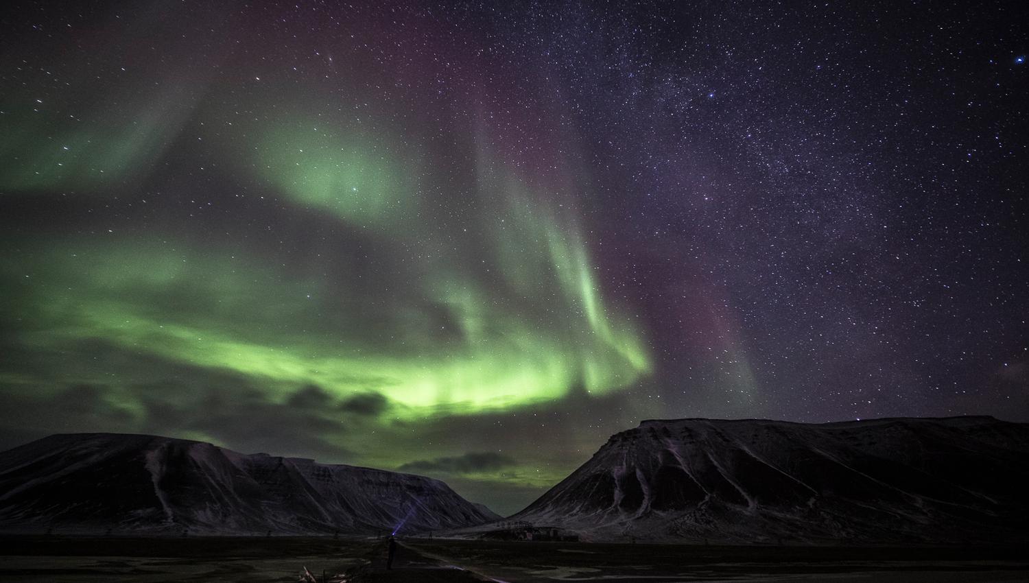 Green northern lights above the mountains