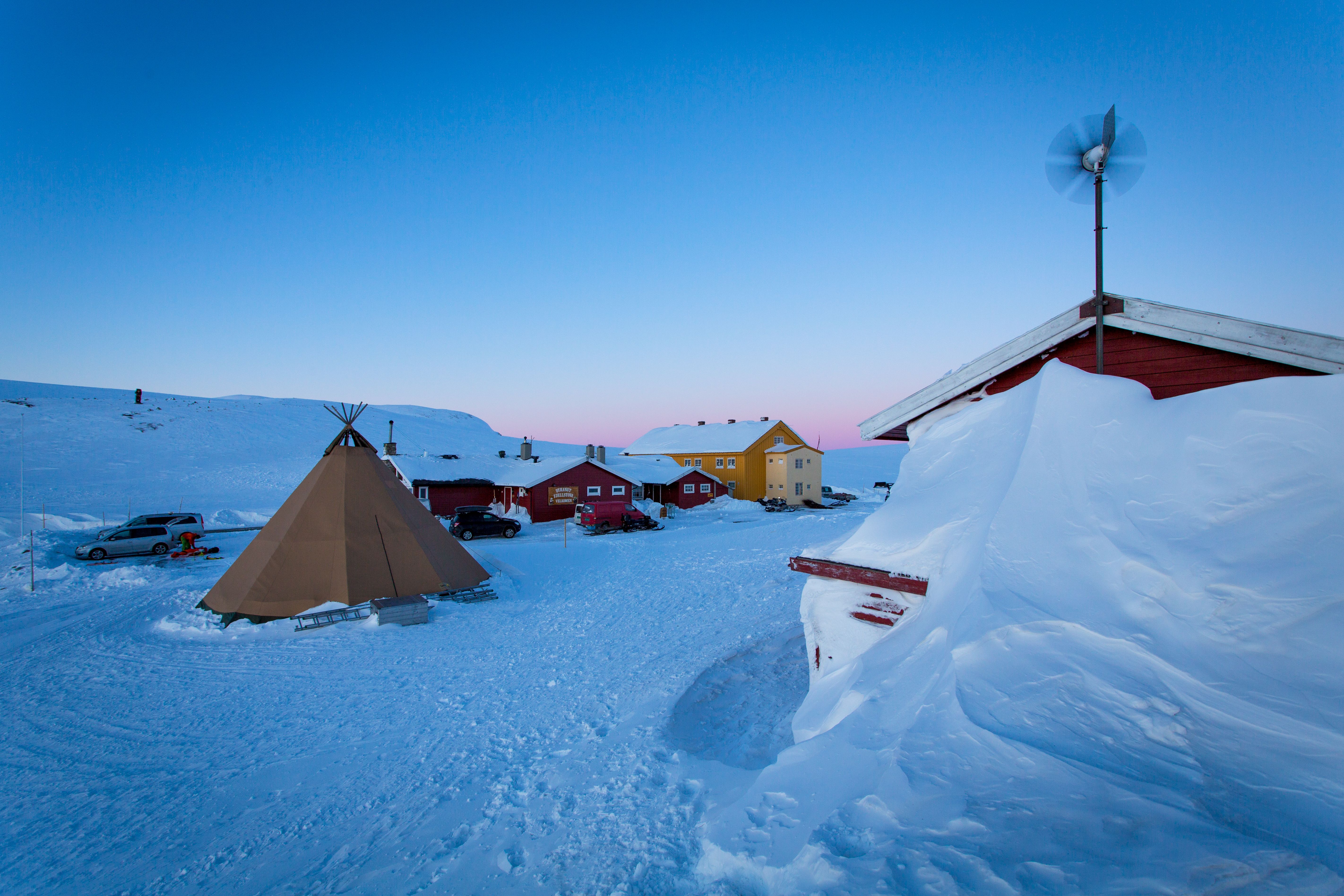 The red Dyranut Fjellstova and yellow Dyranut Turisthytta mountain lodges in snowy landscape.