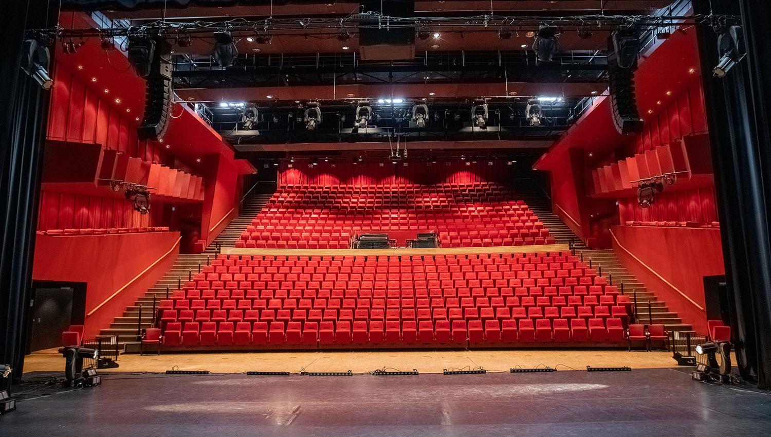 teater- og konsertsal med 20 rekker røde plysjstoler skrånende ned mot scenen.