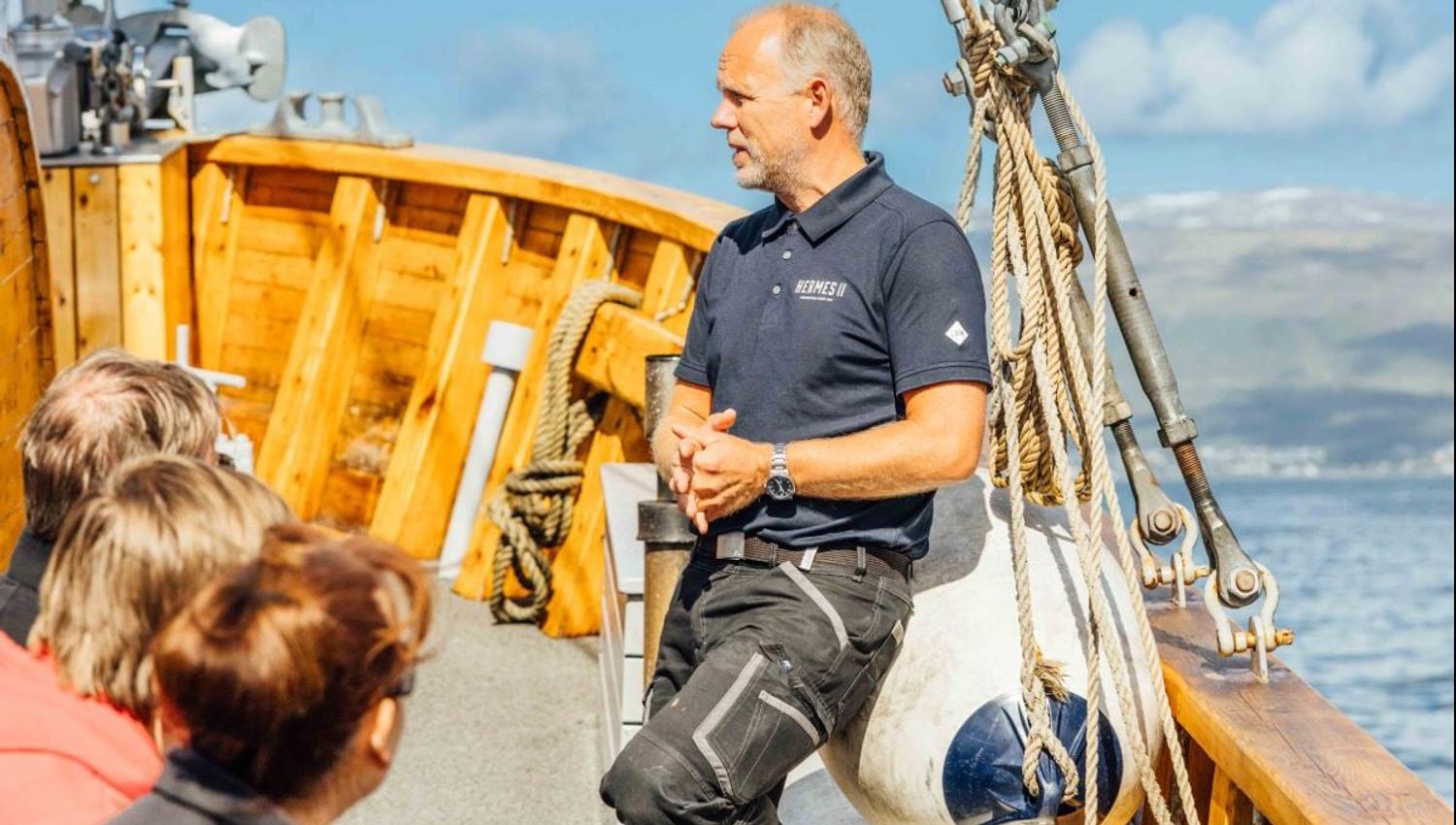Skipperen som deler informasjon med gjestene mens båten seiler