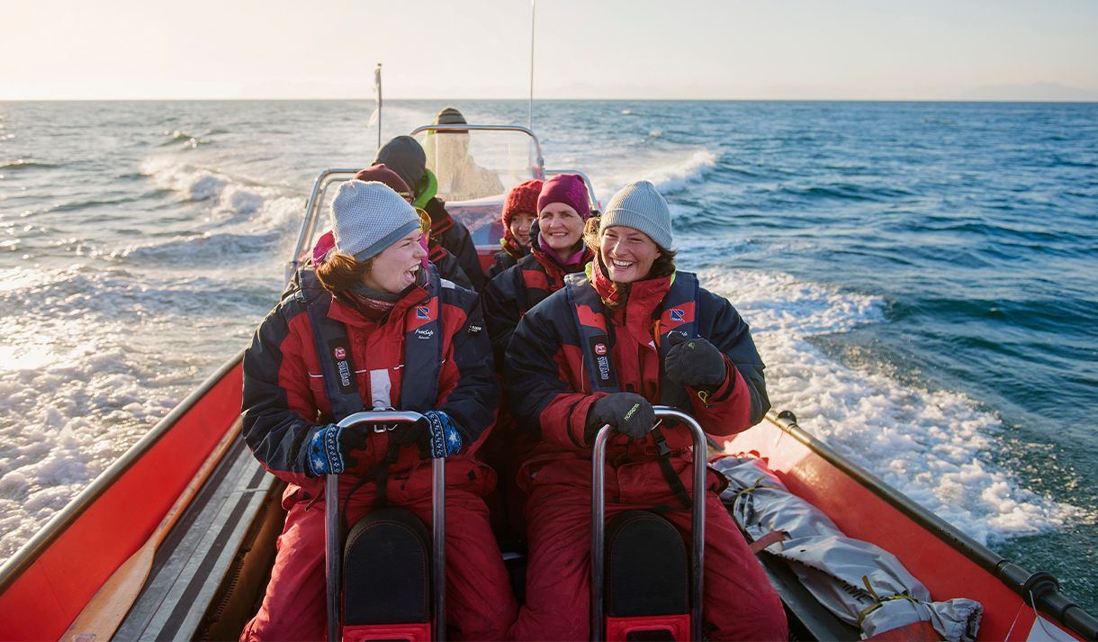 A group of guests on board a RIB boat sailing at speed in a fjord