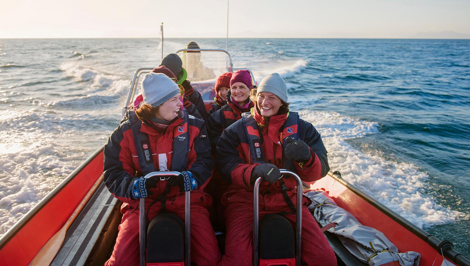 A group of guests on board a RIB boat sailing at speed in a fjord