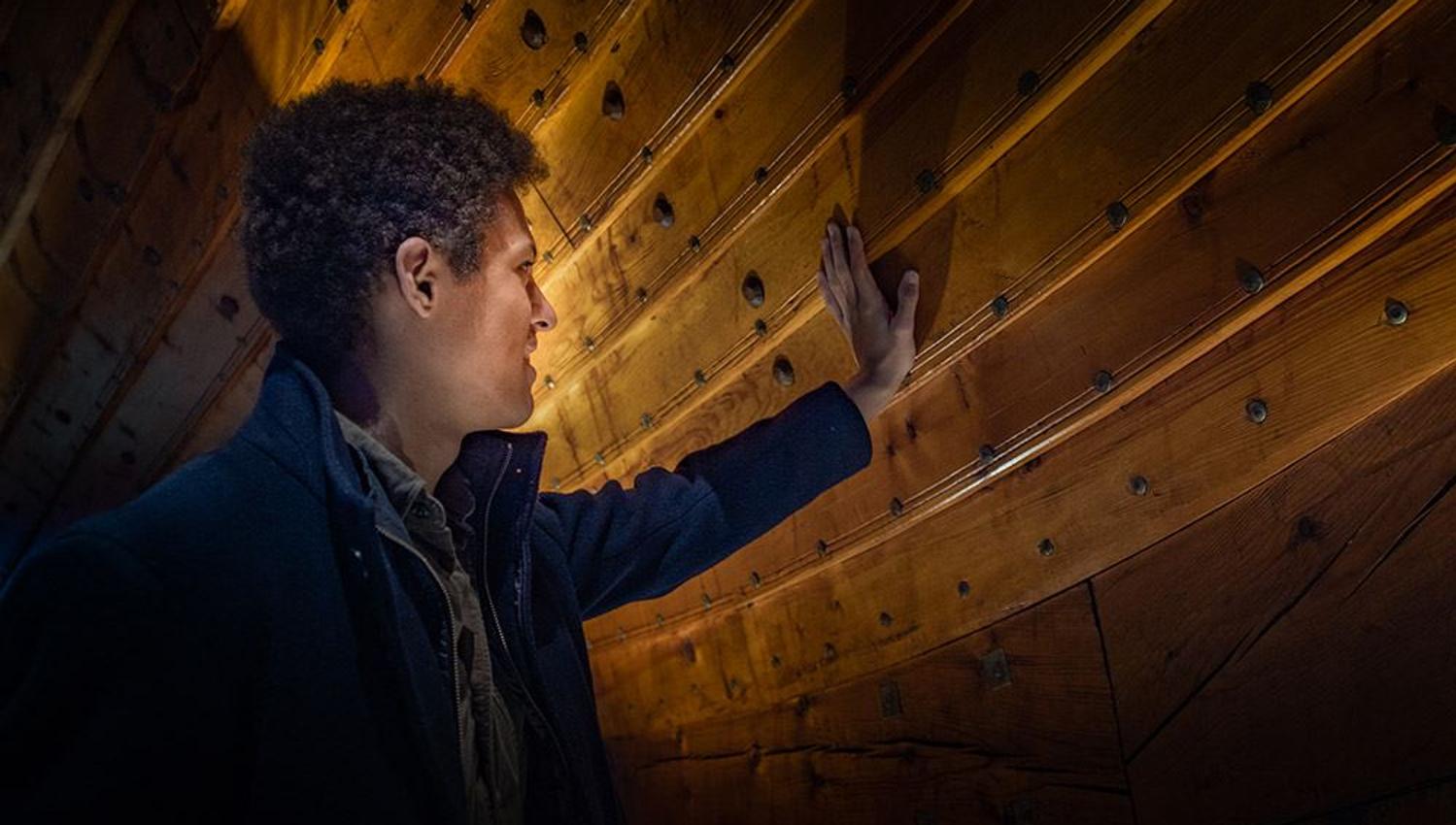 A visitor examining the details of the impressive Viking ship.