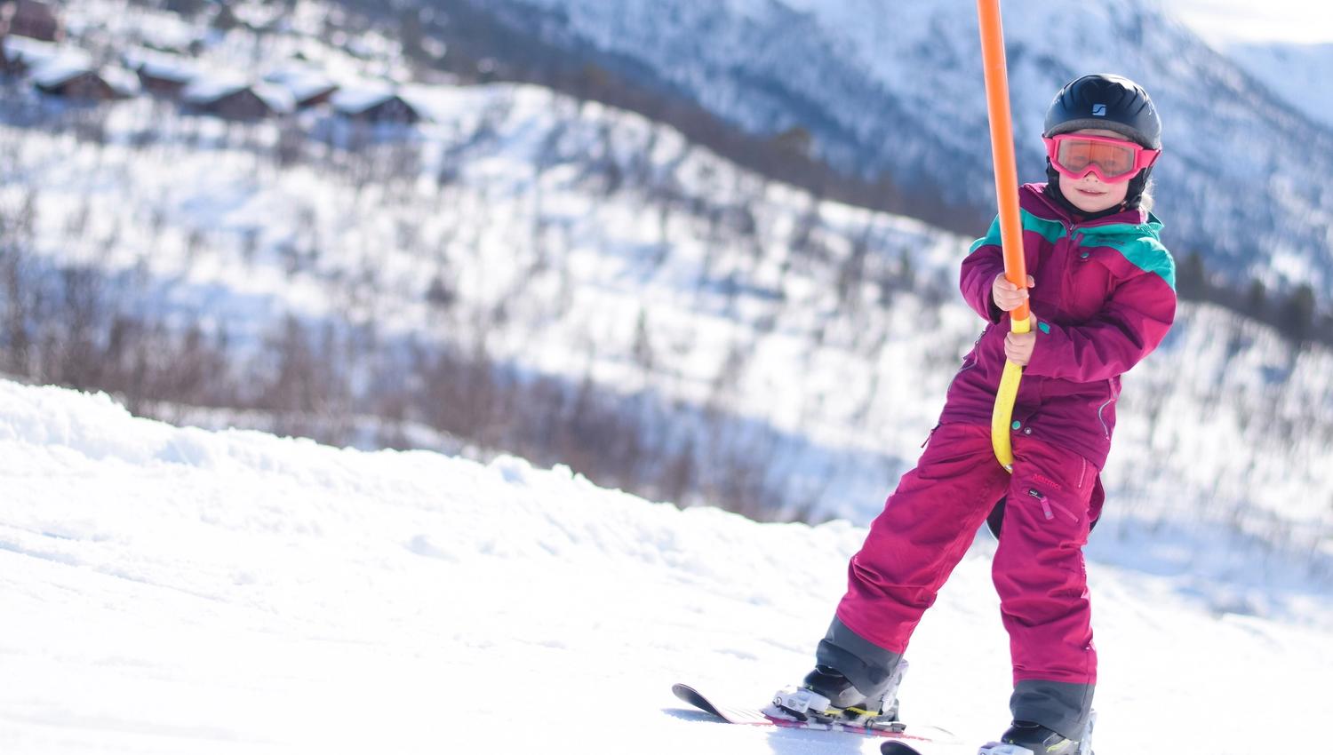 Girl using the ski tow in the children's skiing area, photo