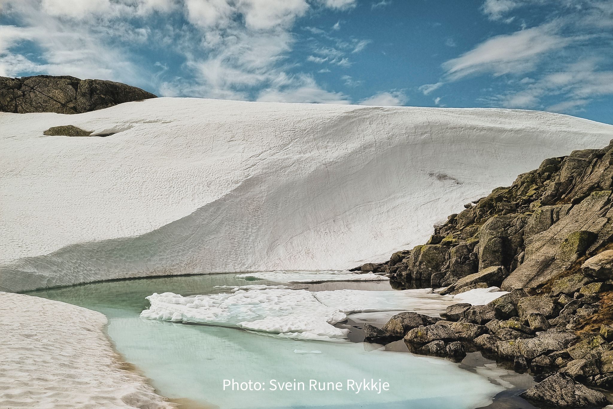 Melting snow and ice by a mountain lake in Hardanger, Norway, marking the arrival of spring
