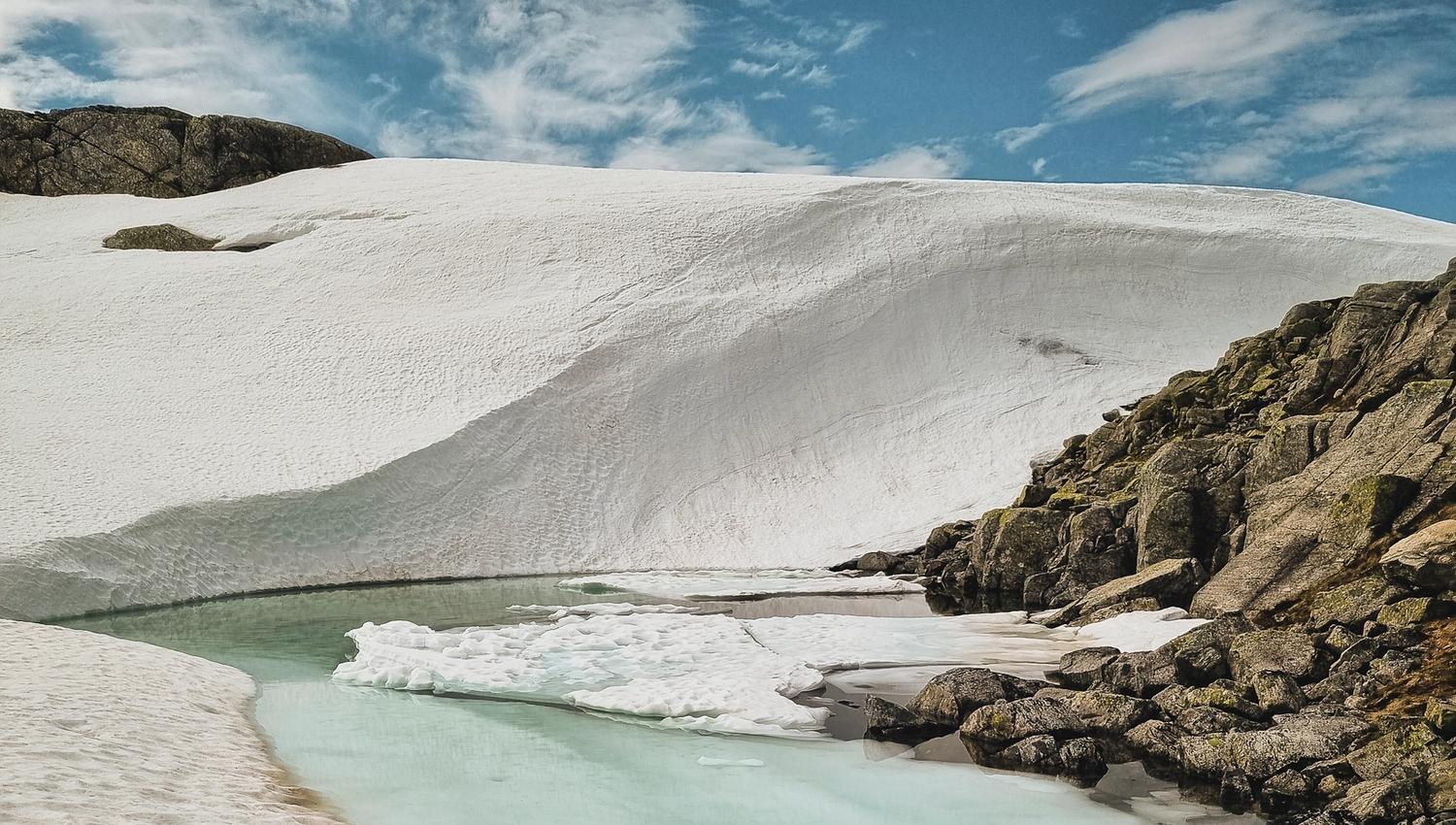 Melting snow and ice by a mountain lake in Hardanger, Norway, marking the arrival of spring