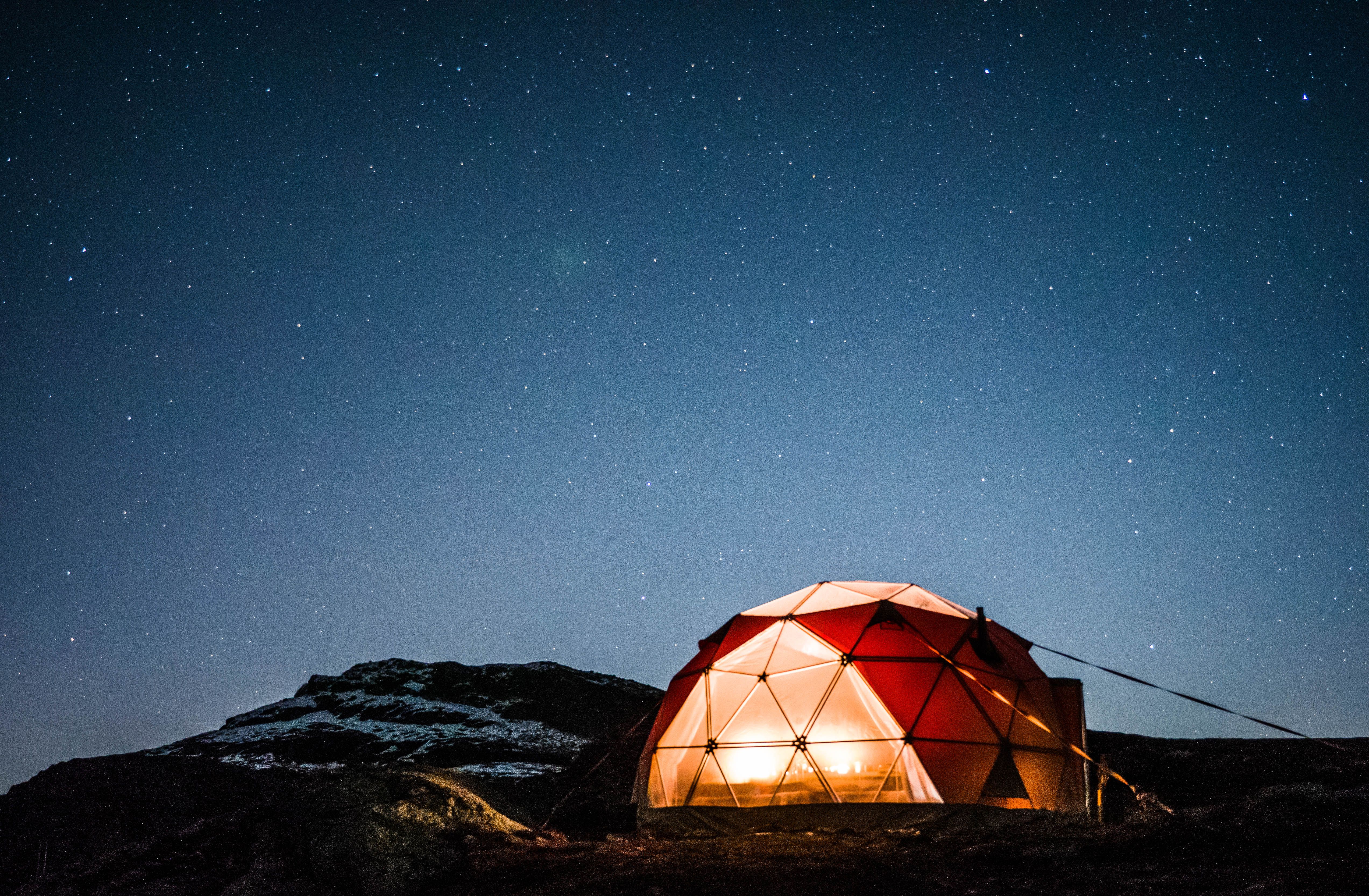 Illuminated glamping dome under a clear starry sky near the Trolltunga mountain plateau.