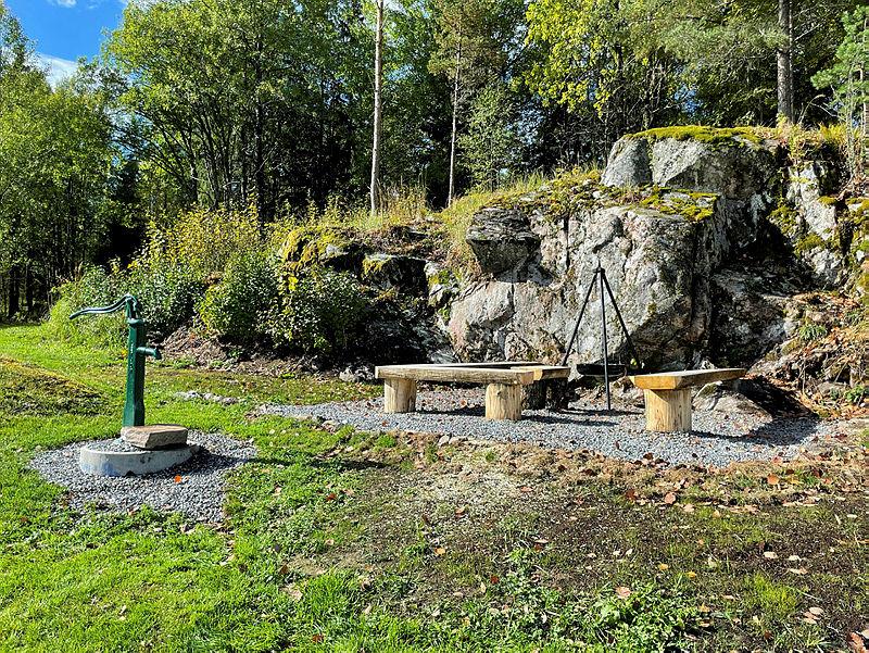 uteområde med benker, bålpanne og brønn