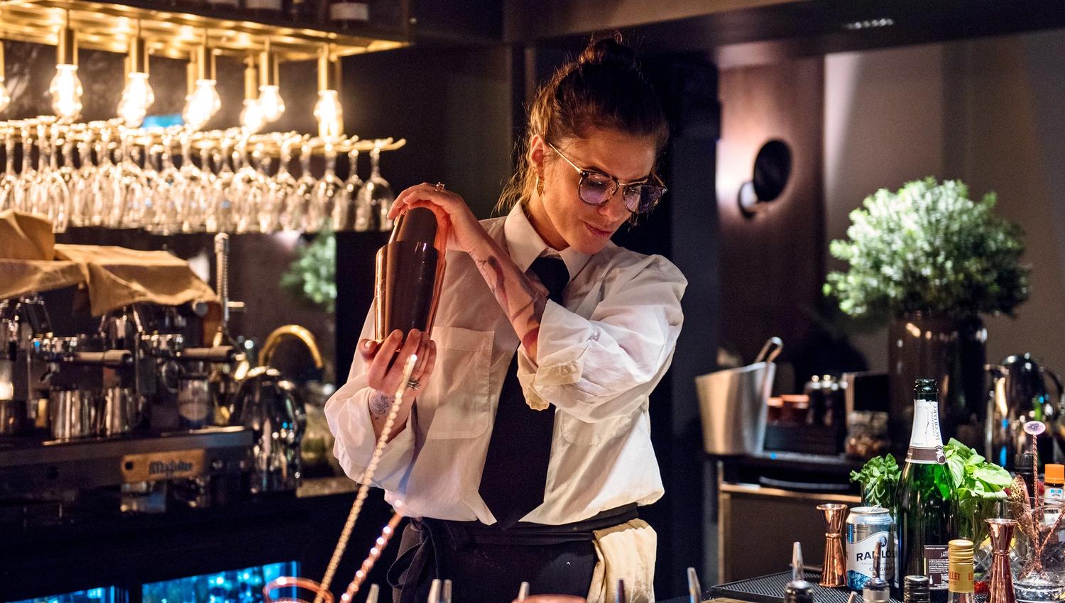 A bartender mixing a drink behind a bar