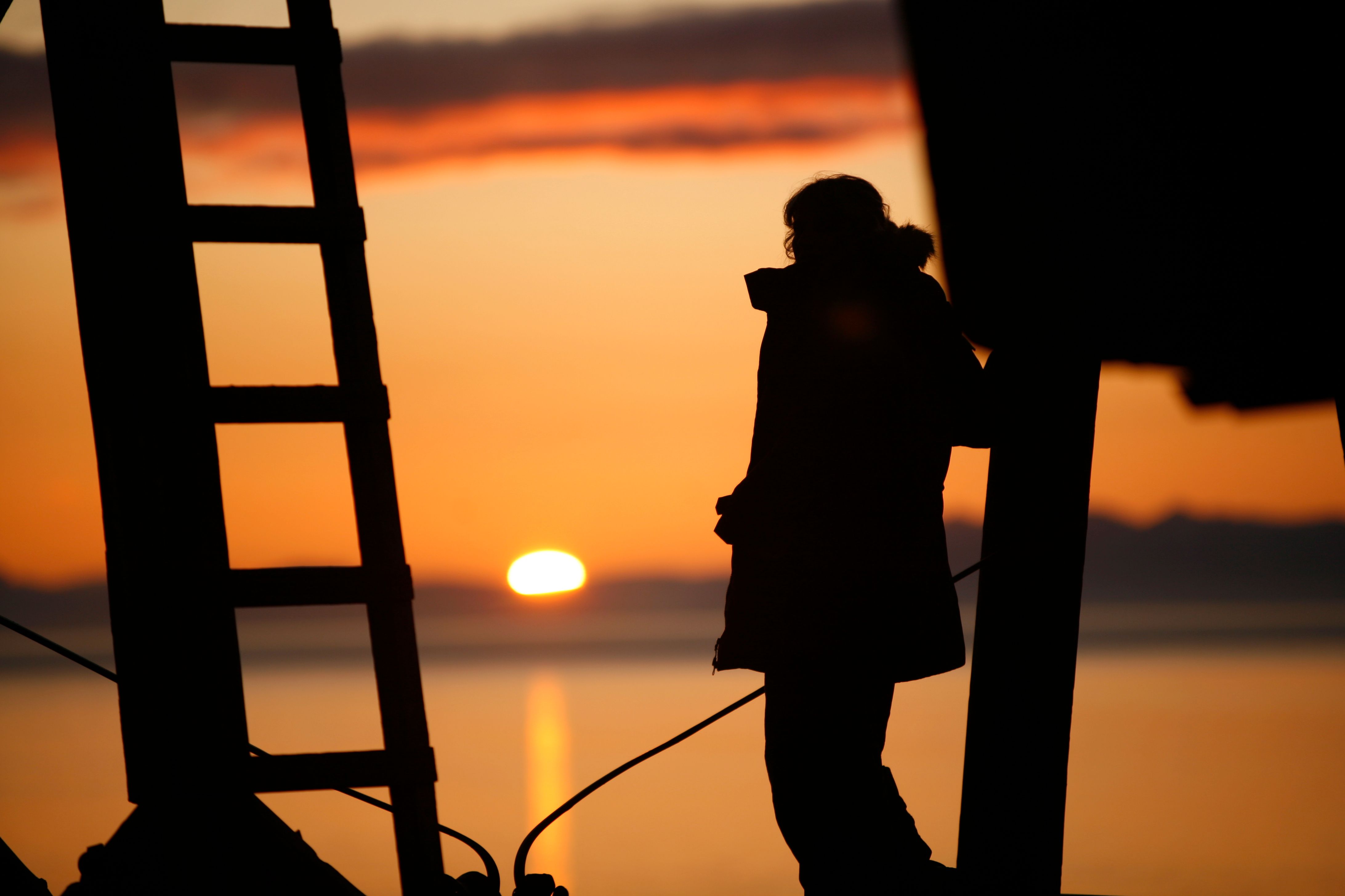 Silhouette of a person looking at the midnight sun 