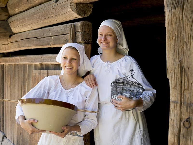 Two young women in front of a traditional wooden building. Norwegian Museum of Cultural History