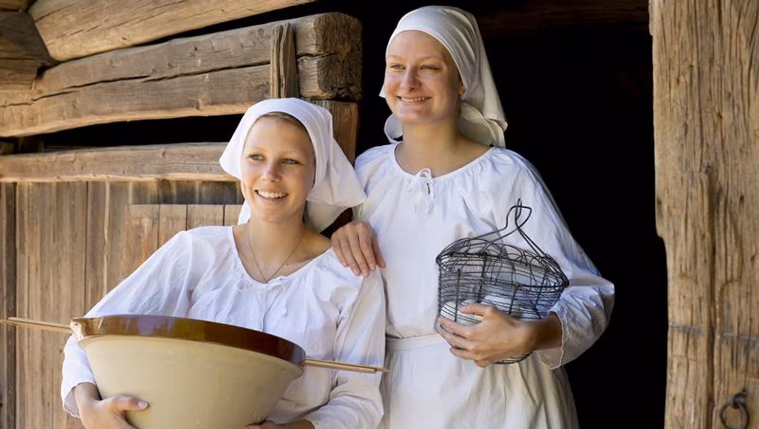 Two young women in front of a traditional wooden building. Norwegian Museum of Cultural History