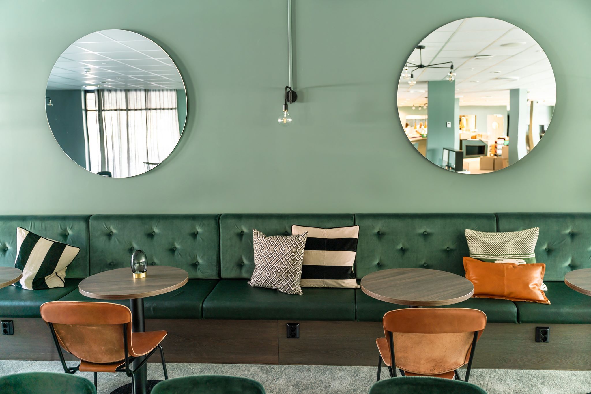 Cozy seating corner with two round mirrors and green sofa cushions.