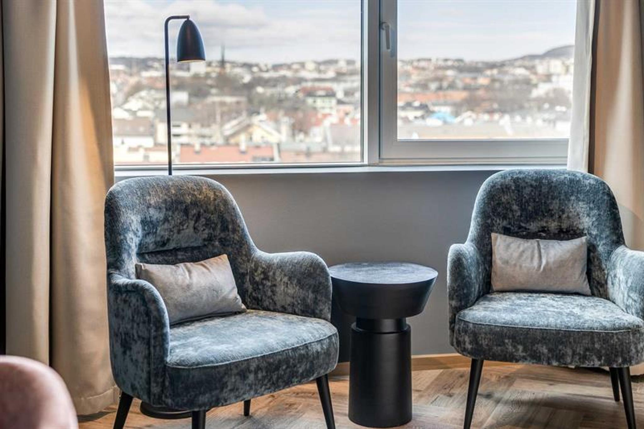 Detail of two blue armchairs in front of a window with a view of north-eastern Oslo