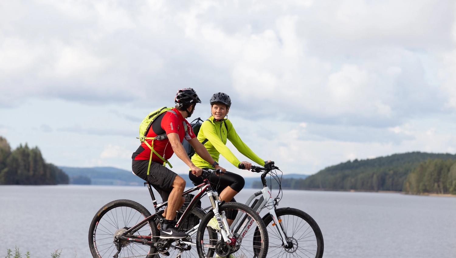 A couple going by bike beside a lake