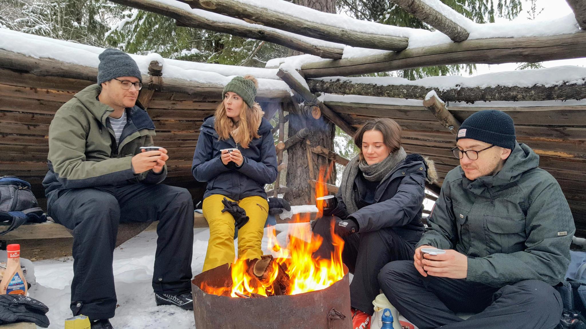 4 people around a fire drinking coffee in wintertime 