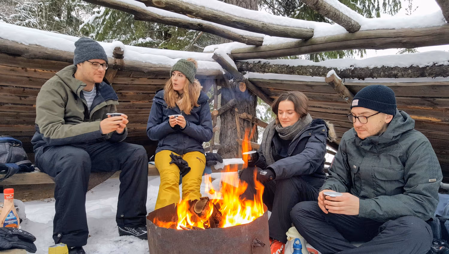4 people around a fire drinking coffee in wintertime