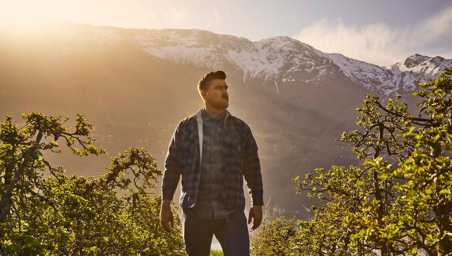 Man walking through a blossoming apple orchard in Hardanger during springtime.