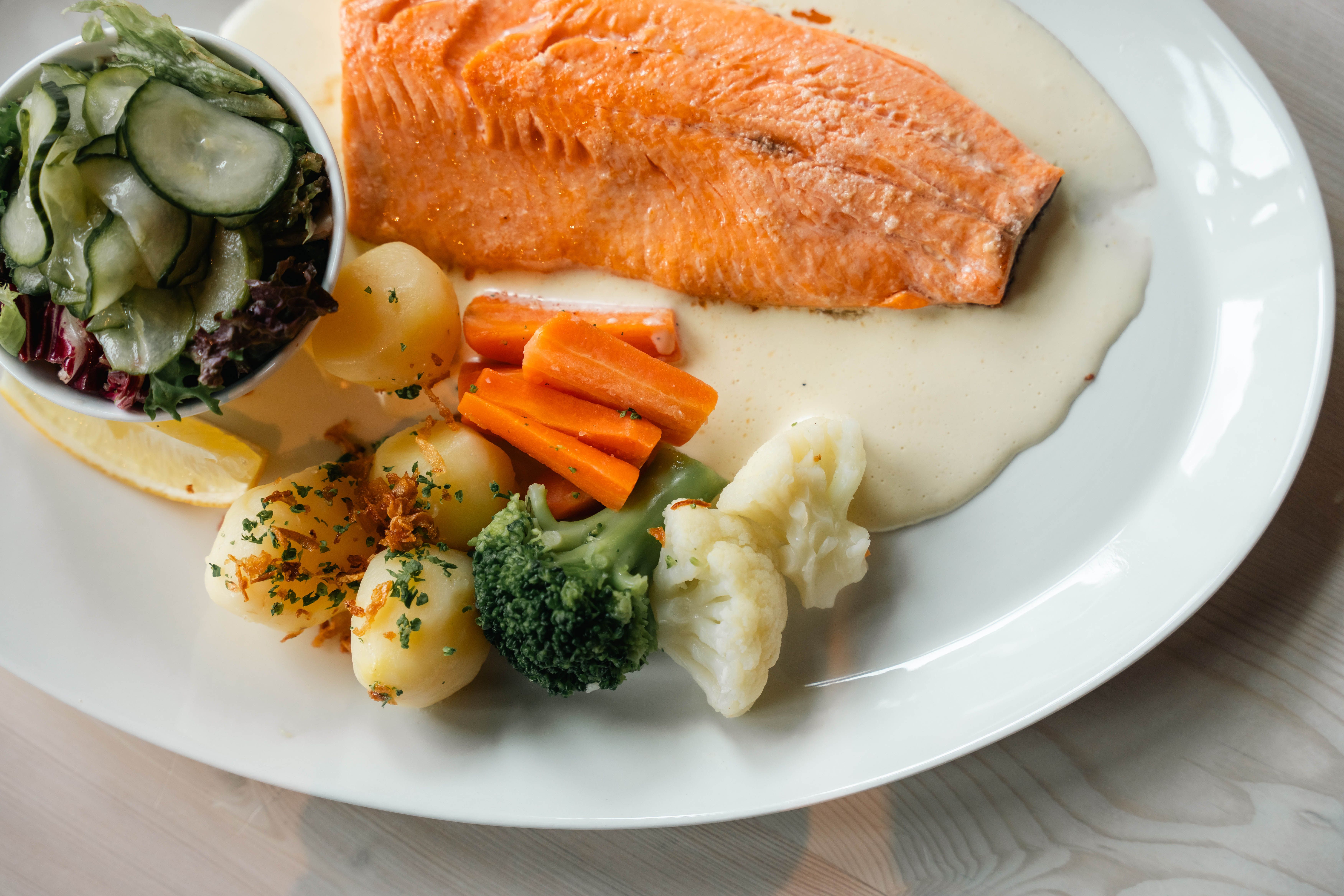 A plate with mountain trout, potatoes, salad and cream sauce.