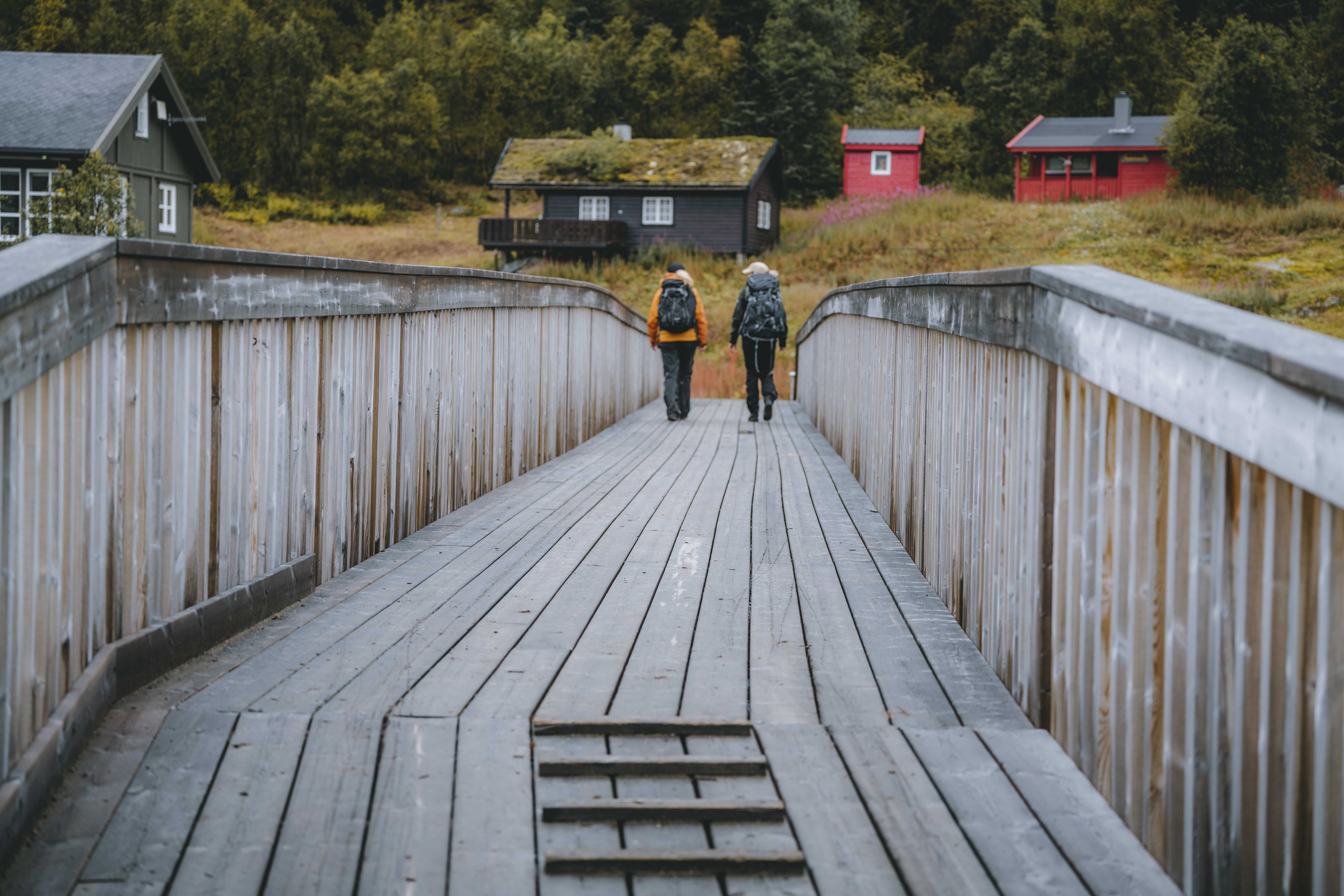 Zwei Wanderinnen überqueren die Brücke über den Fluss in Richtung Vivelid.