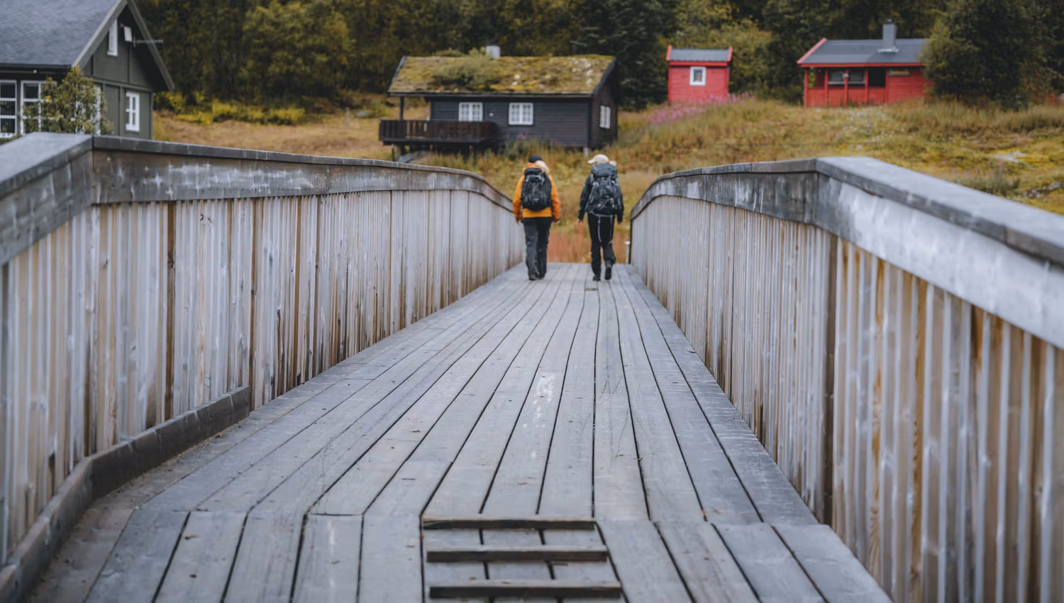 Zwei Wanderinnen überqueren die Brücke über den Fluss in Richtung Vivelid.