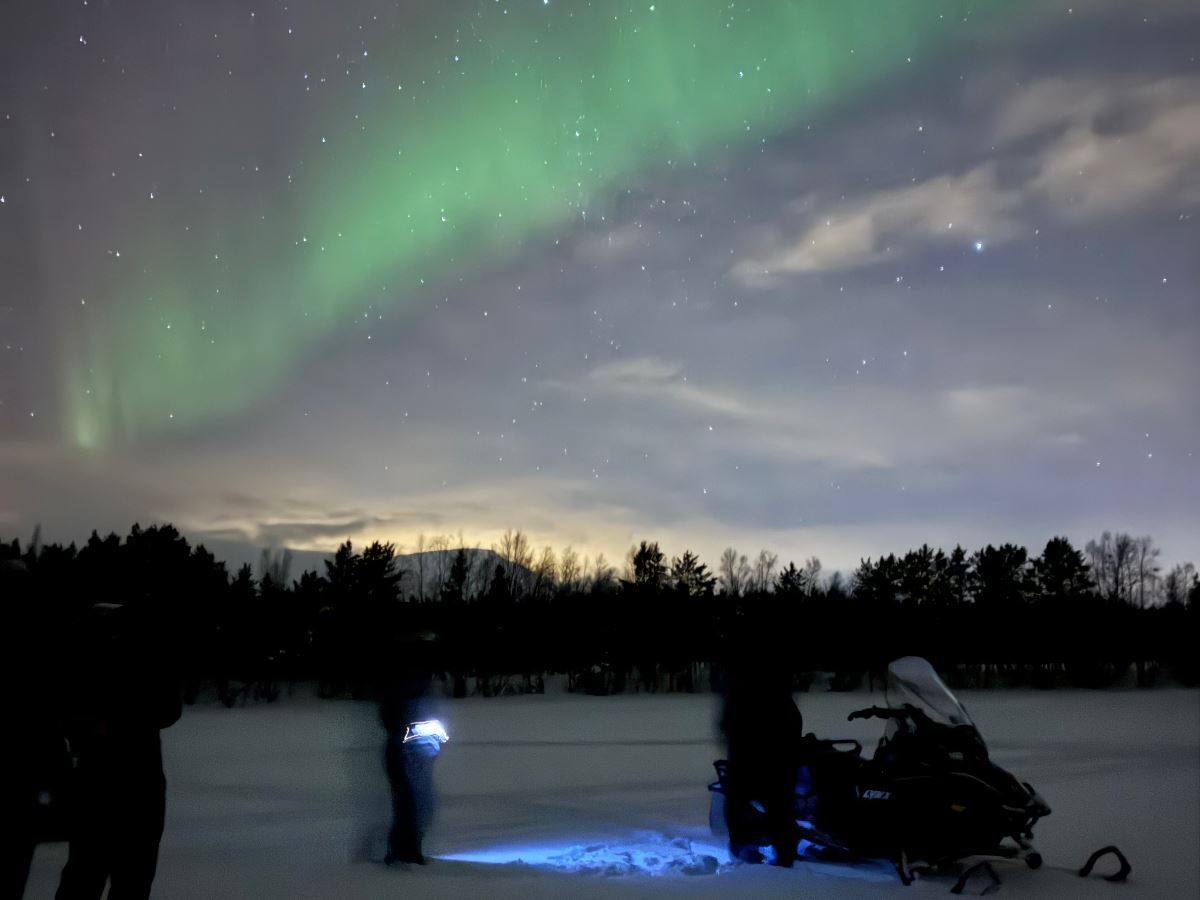 Guests with snowmobiles under the Northern Lights in Skibotn Valley