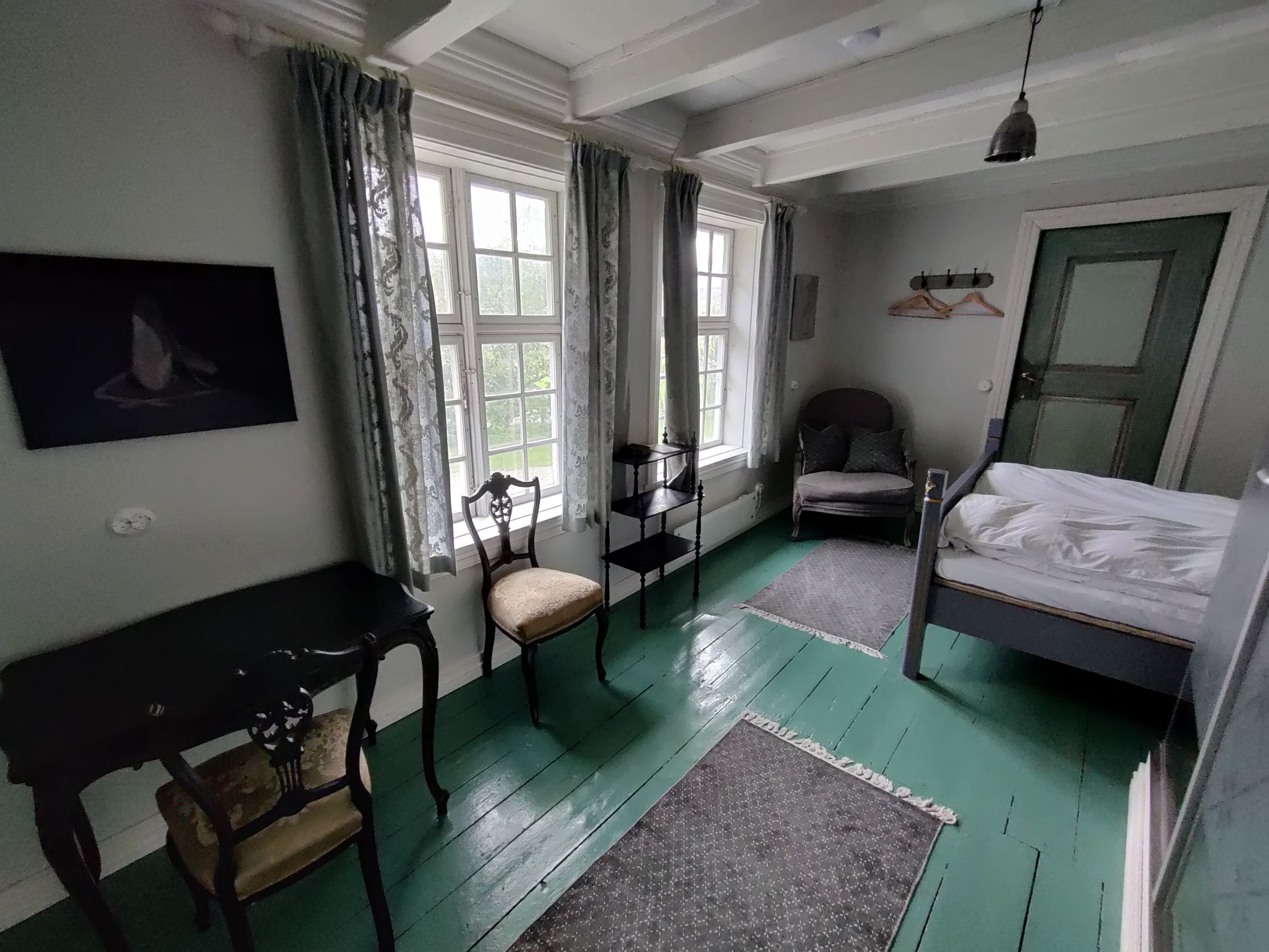 A cosy salon at Skrivergaarden with classic furniture, green walls and large windows.
