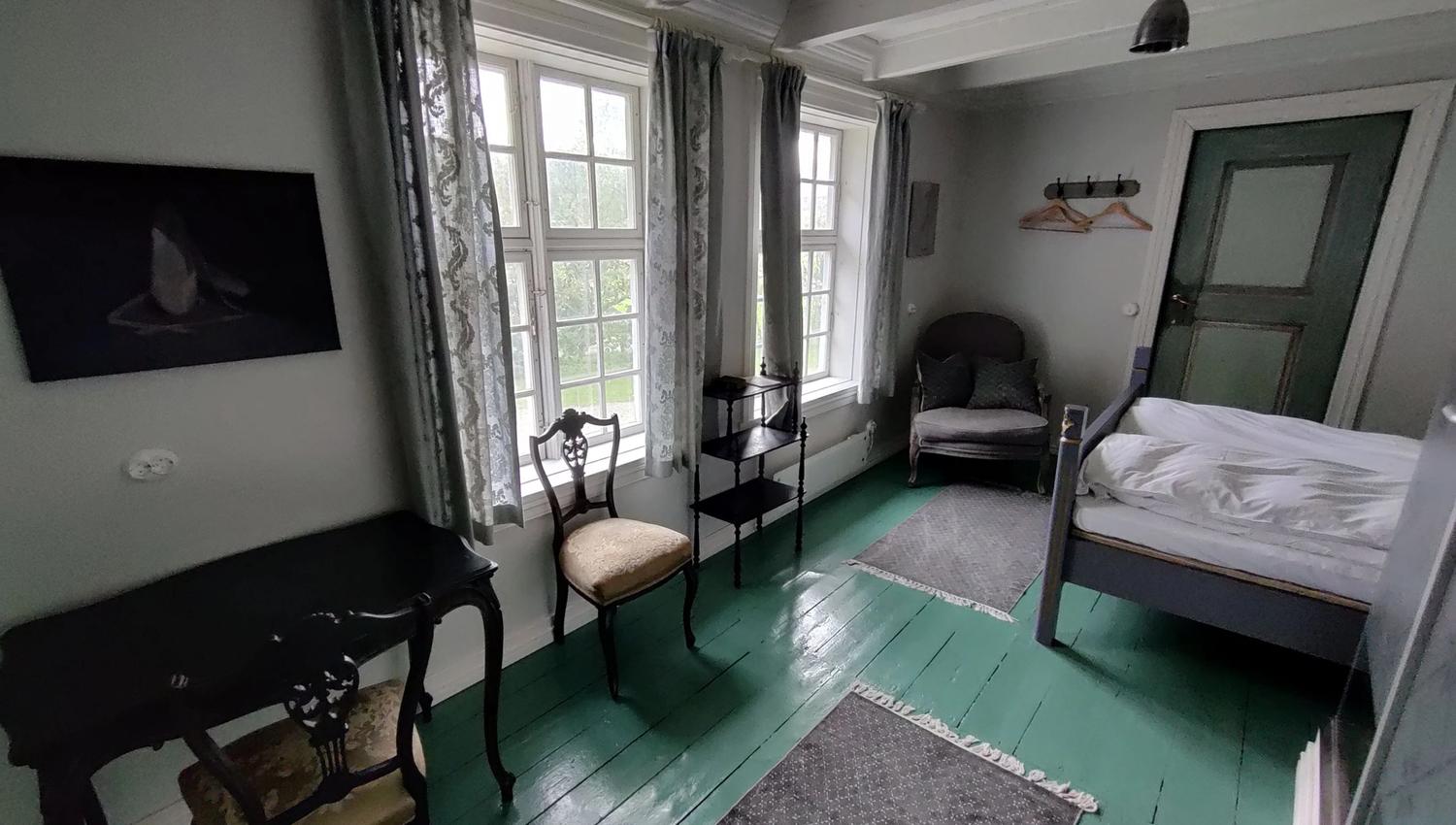 A cosy salon at Skrivergaarden with classic furniture, green walls and large windows.
