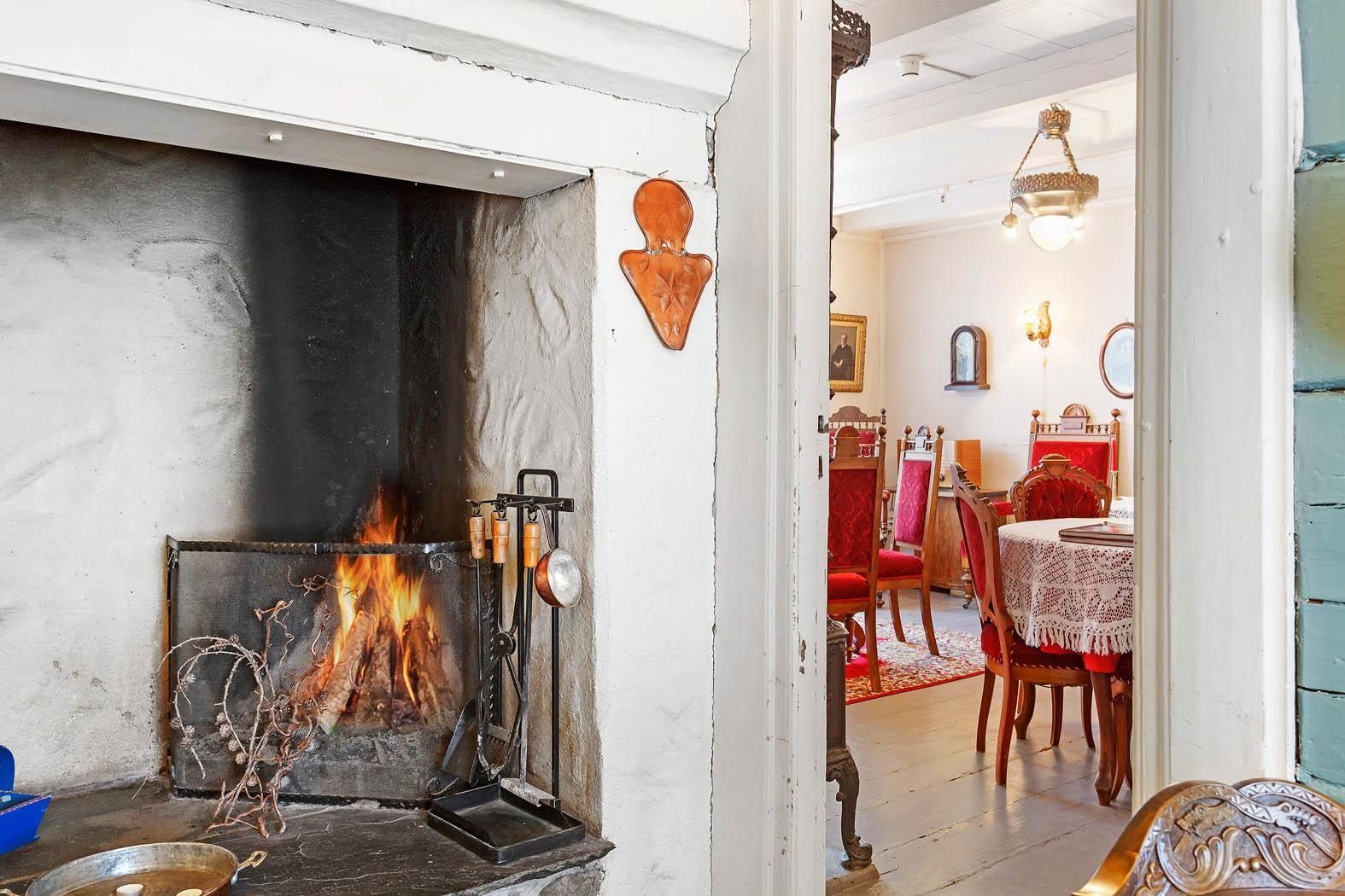 Open fireplace and nostalgic dining room with red chairs at Jaunsen Guesthouse in Hardanger.