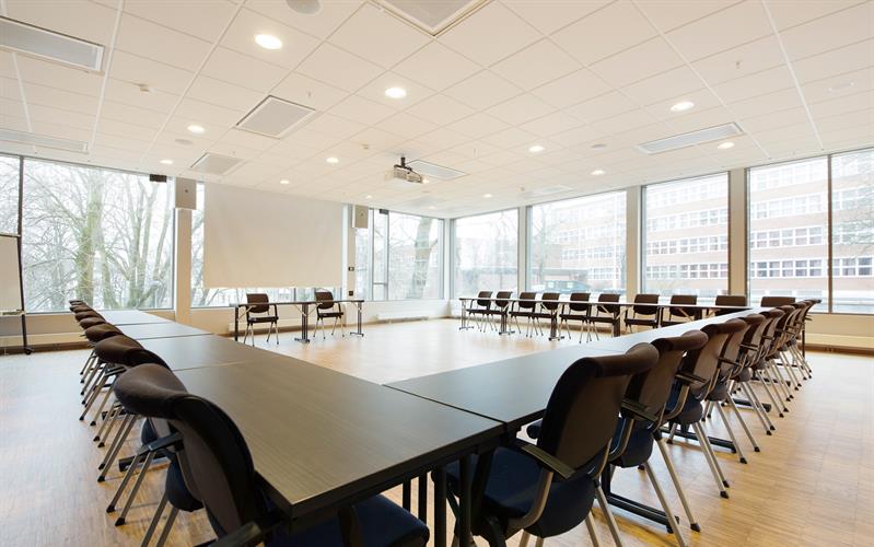 bright and large conference hall with tables in horseshoe-setup and conference technology