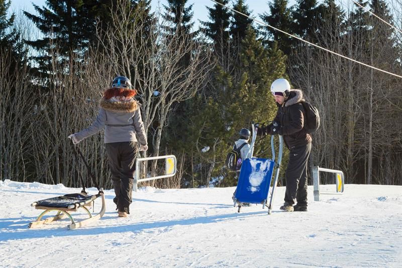 Two people pulling their sleds at the bottom of the hill.