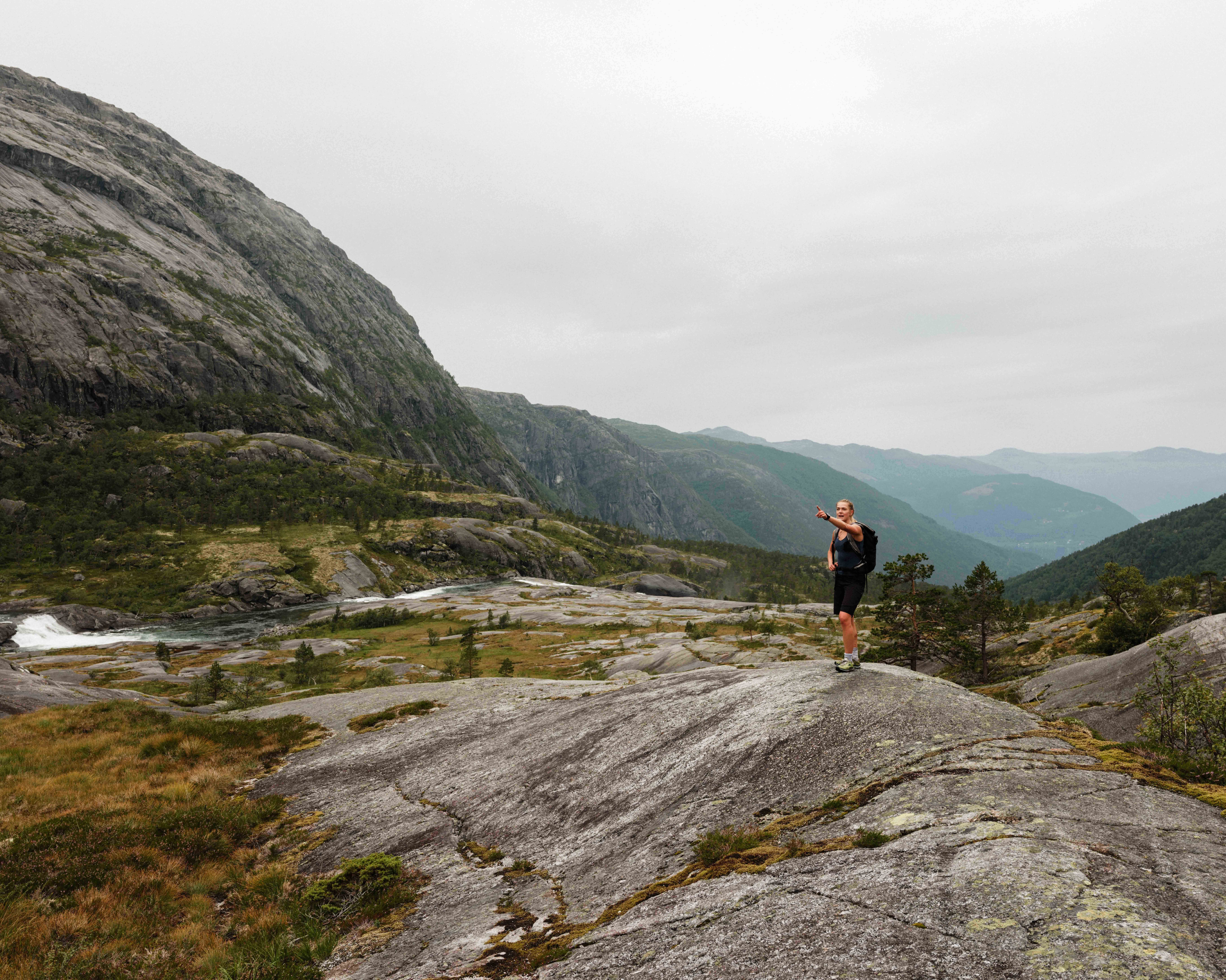 Hiker overlooking the fjord landscape while ascending Husedalen – stunning views of Hardanger.