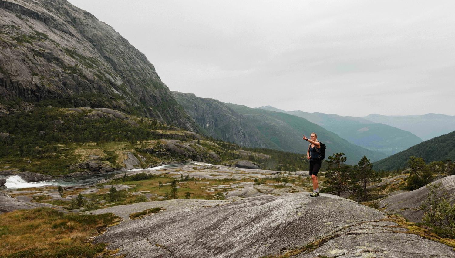 Hiker overlooking the fjord landscape while ascending Husedalen – stunning views of Hardanger.