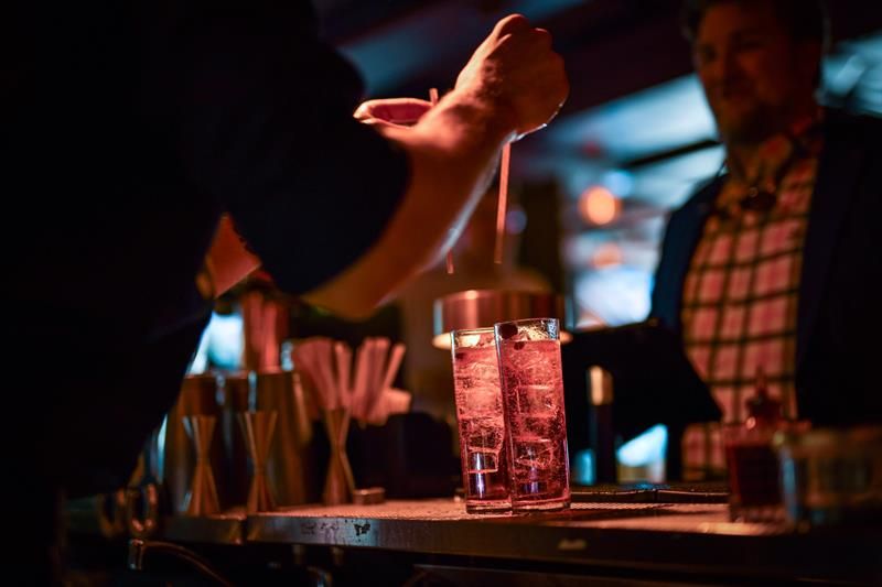 Bartender som putter to sugerør i to drinker