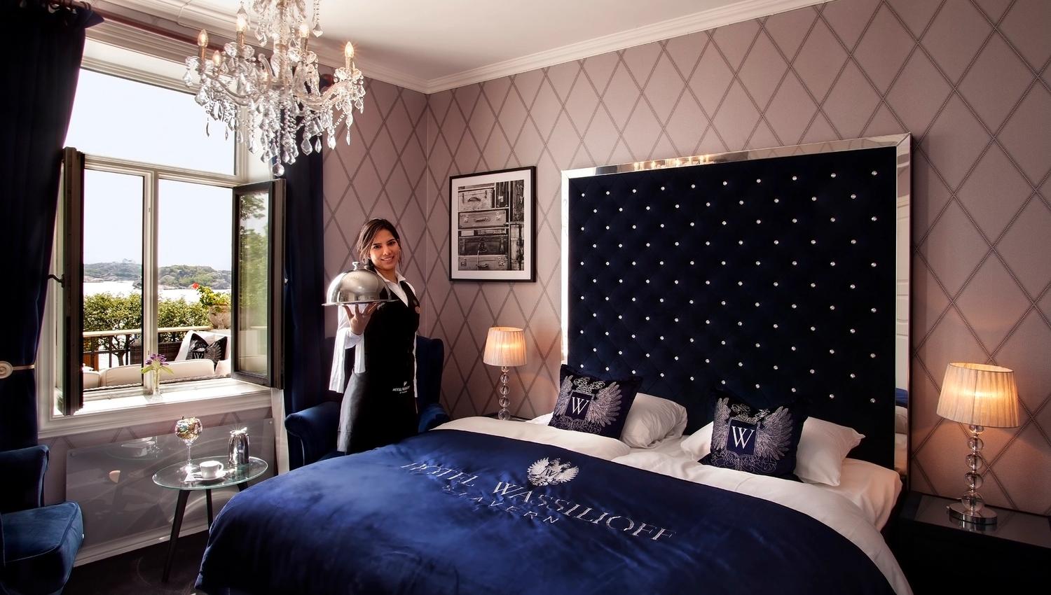 A maid holds out a serving dish inside a hotel room.