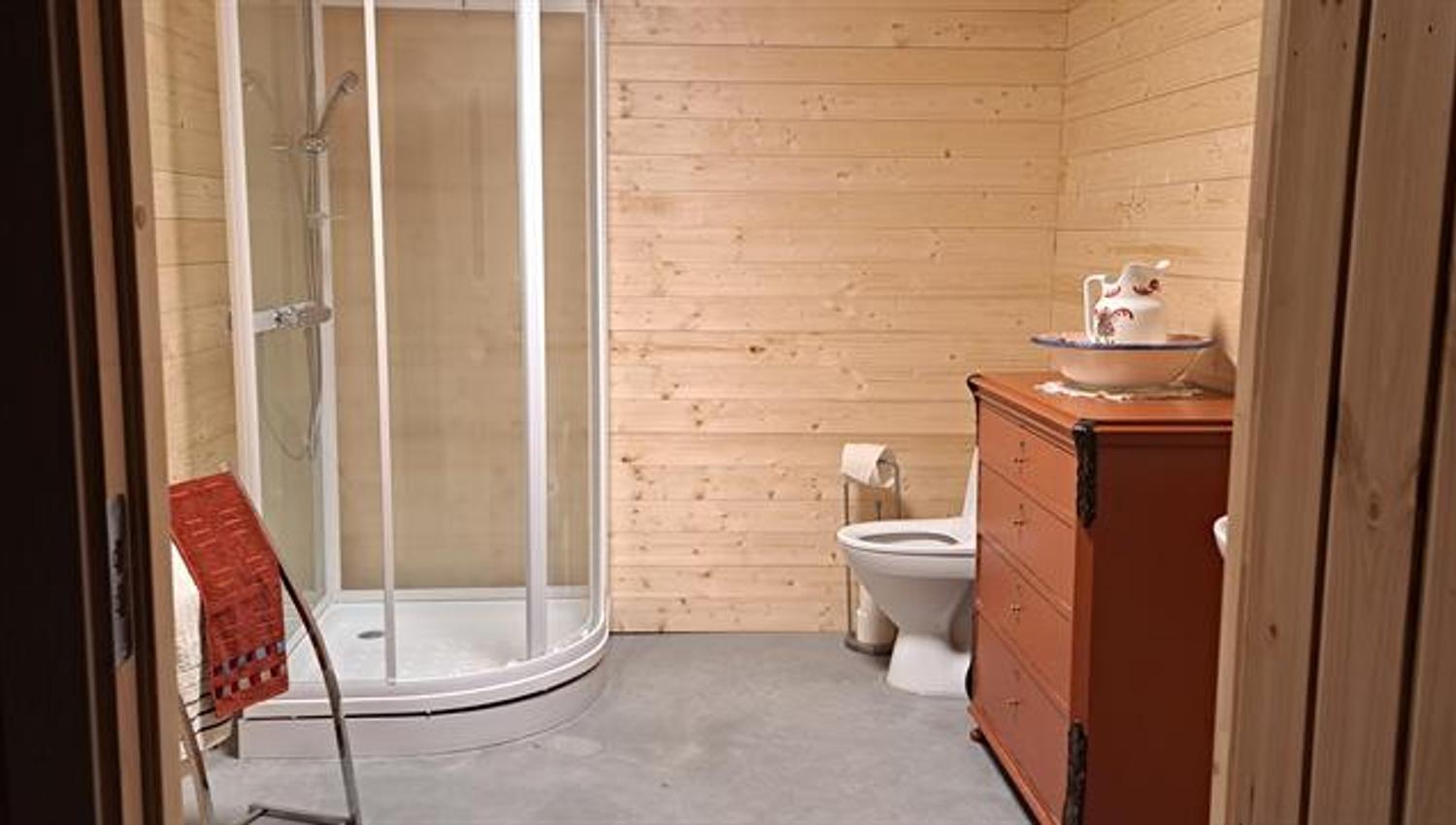 Bathroom with shower, toilet and sink in adjacent building next to Gjeterhytta