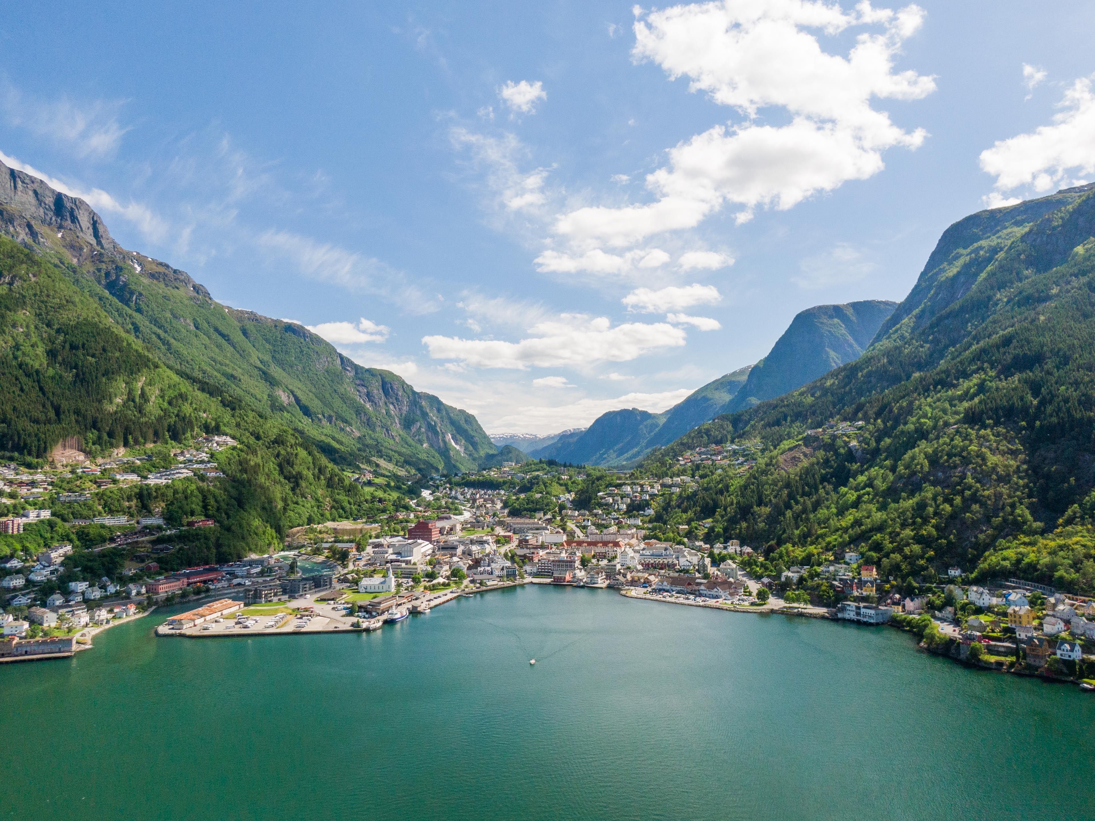 Aerial photo of Odda by the fjord with houses and boats along the waterfront.