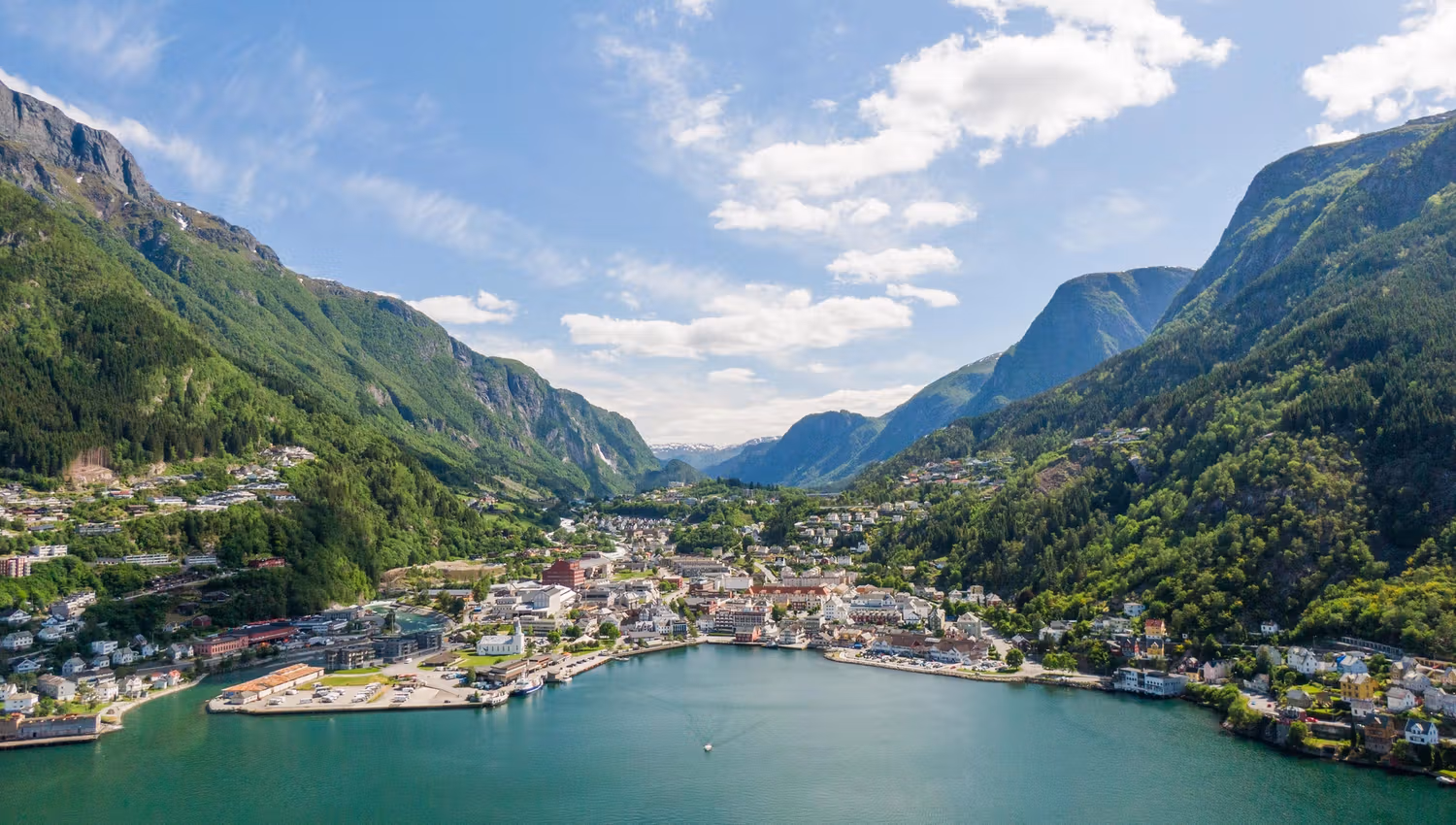 Aerial photo of Odda by the fjord with houses and boats along the waterfront.