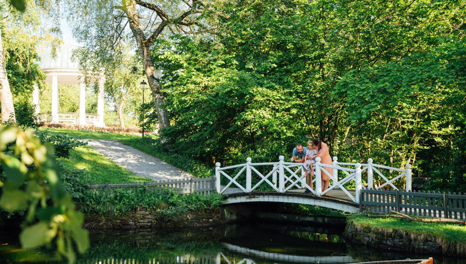 family standing on a bridge over the duck pond in Brekkeparken in Skien